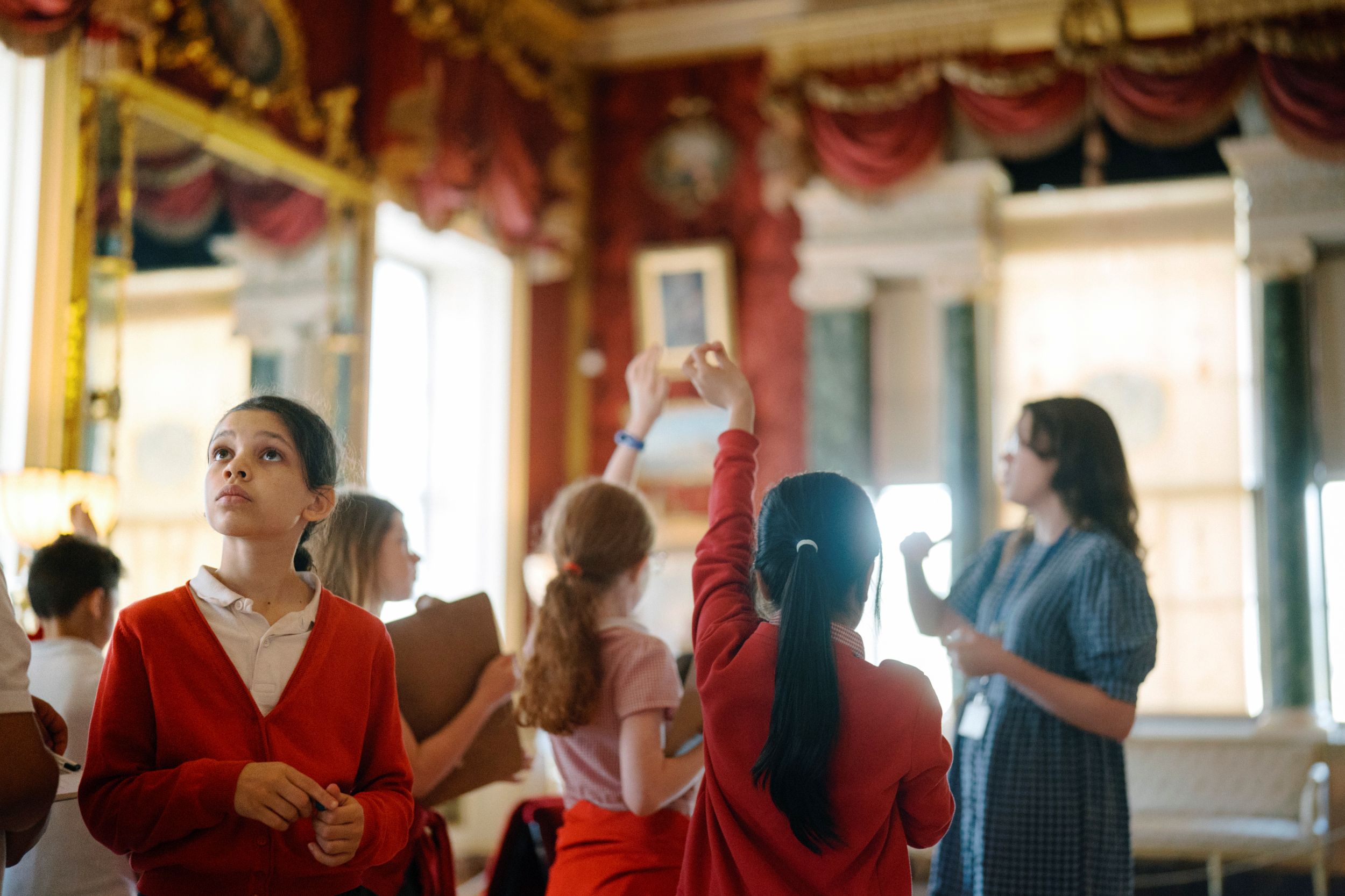 Children exploring an ornate room with red walls and gold accents