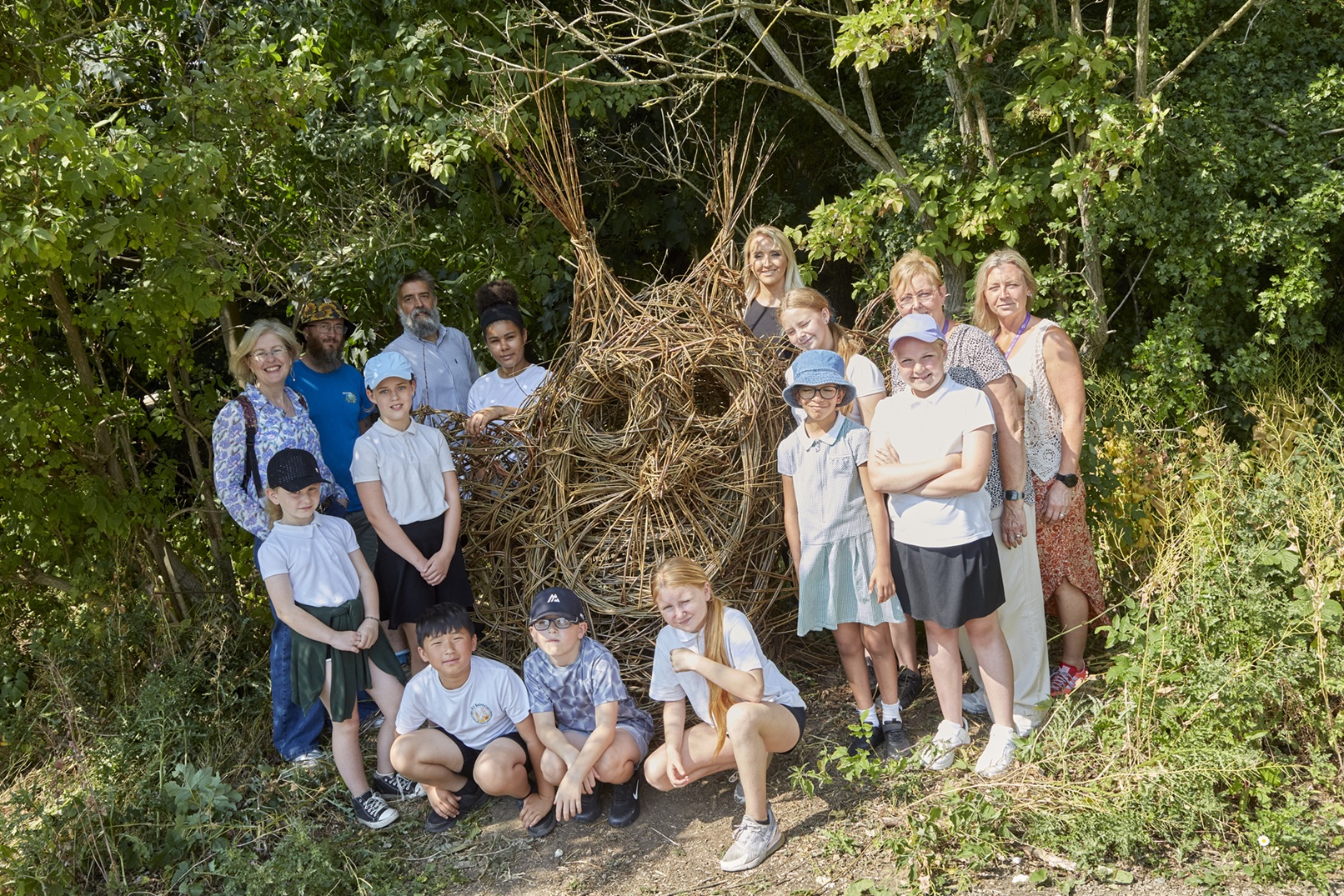 Group of children and adults with woven woodland sculpture