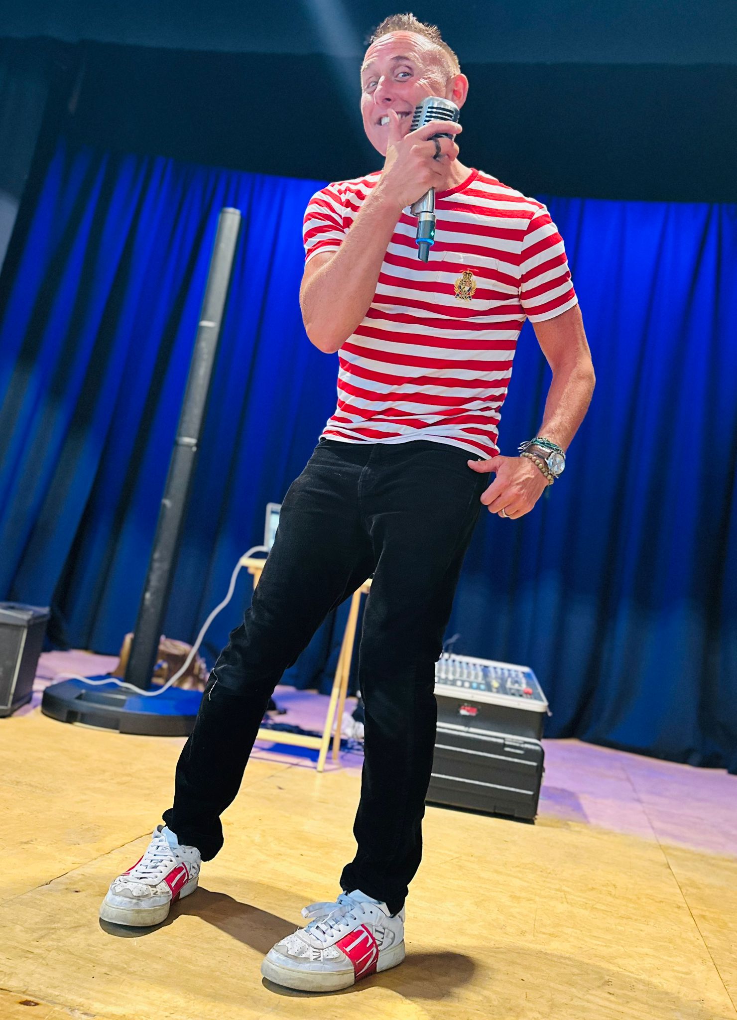 Performer in red and white striped shirt on stage with microphone