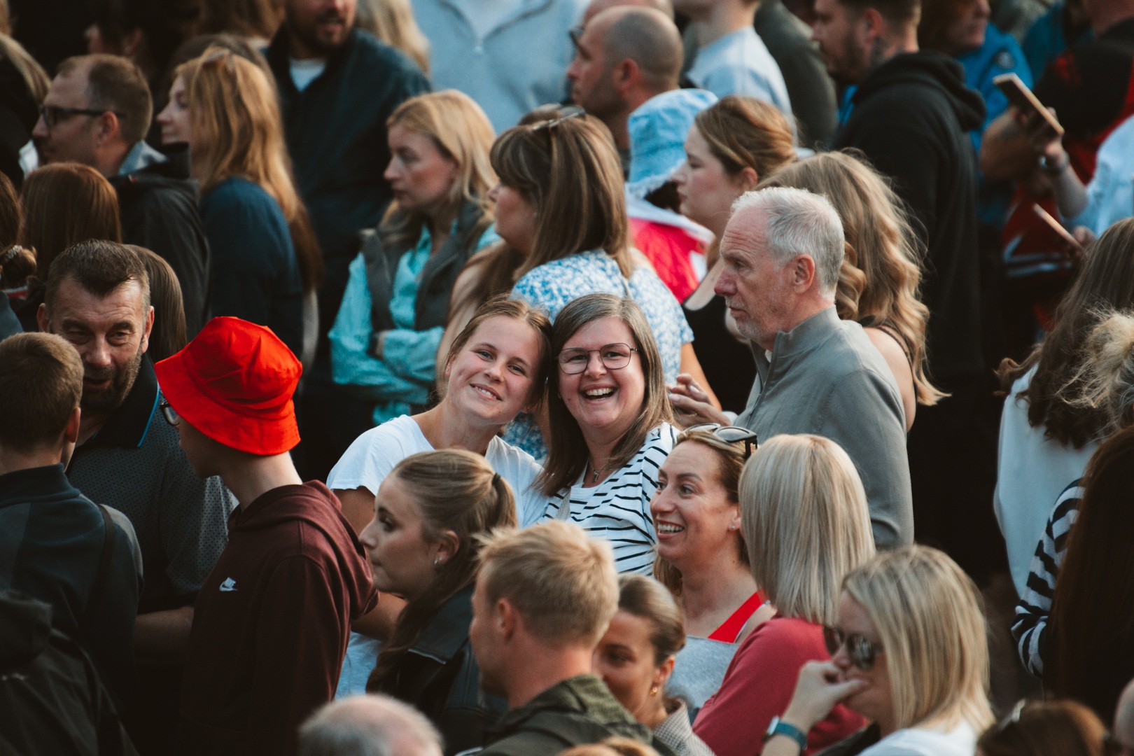 Crowd of people smiling and enjoying a sunny outdoor event