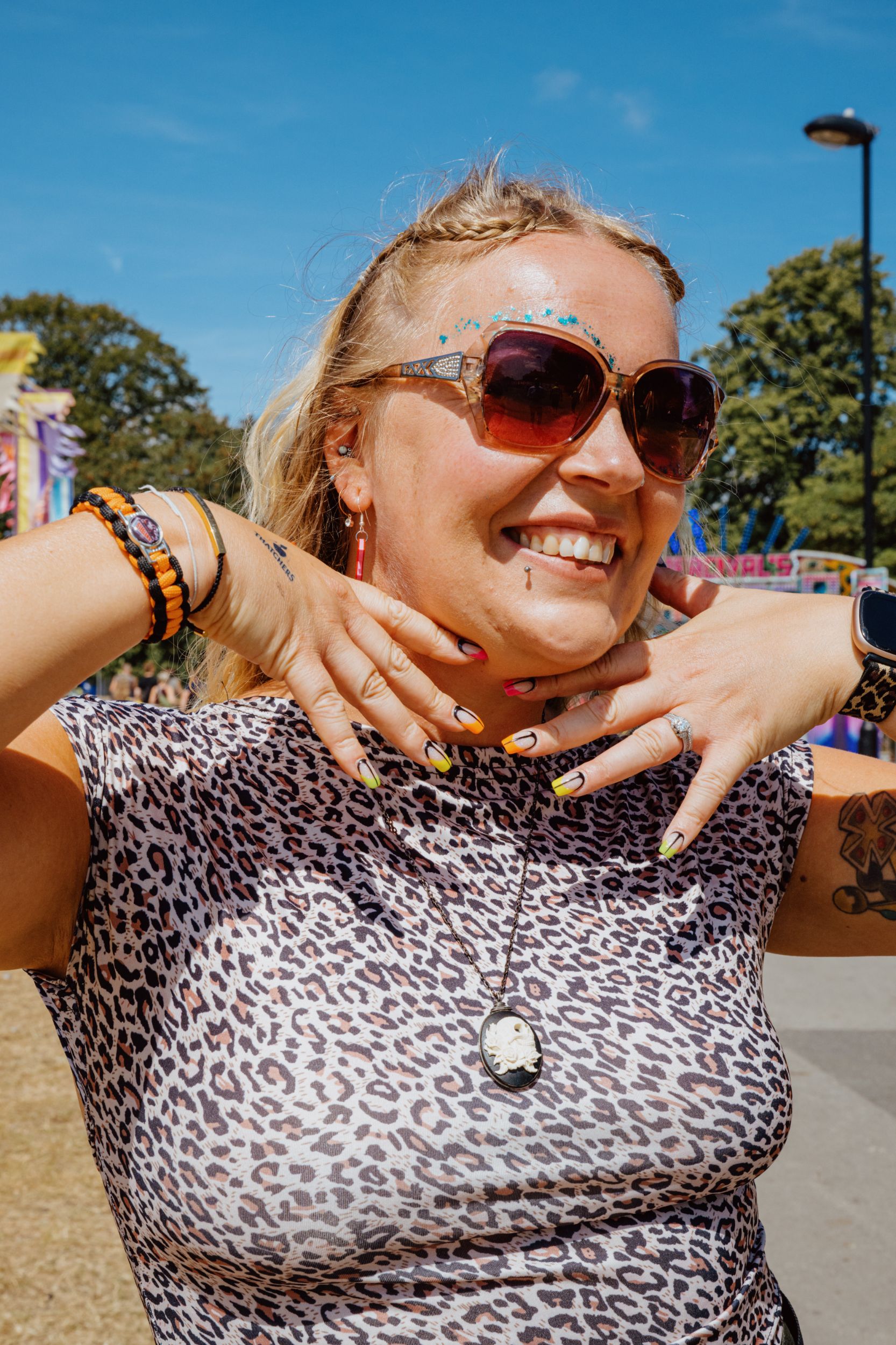 Smiling woman with sunglasses and glitter at outdoor festival