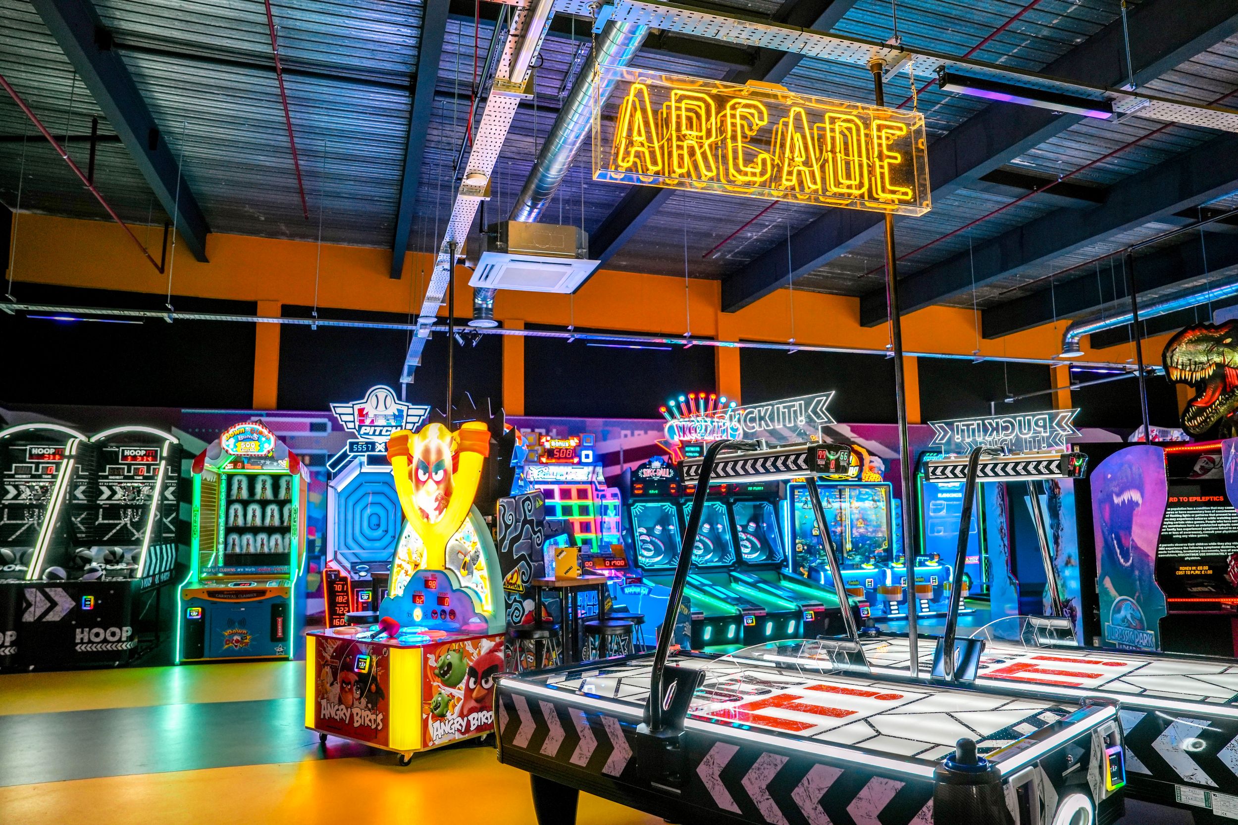 Brightly lit arcade with neon sign and colourful game machines
