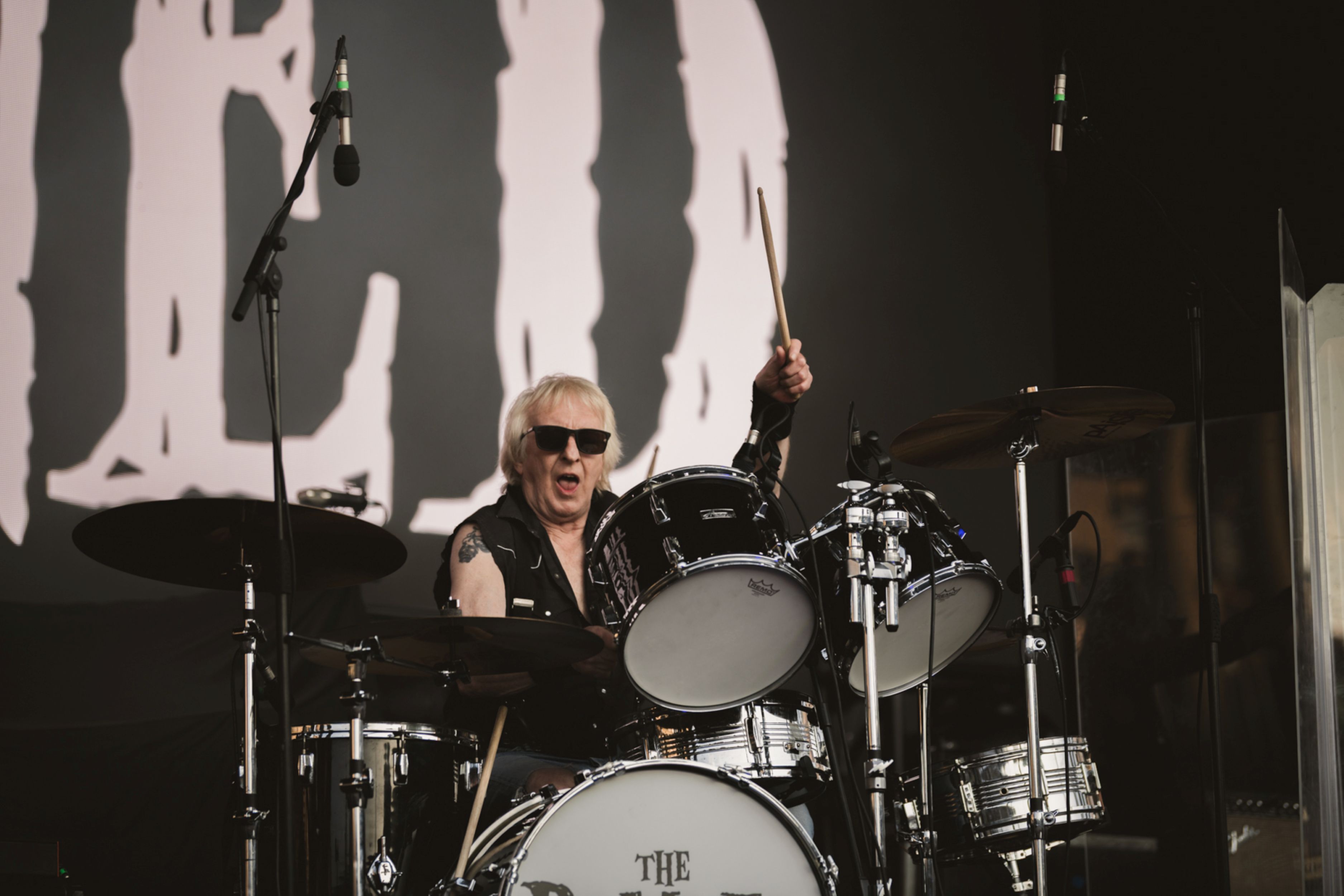 Drummer energetically playing on stage with dramatic lighting