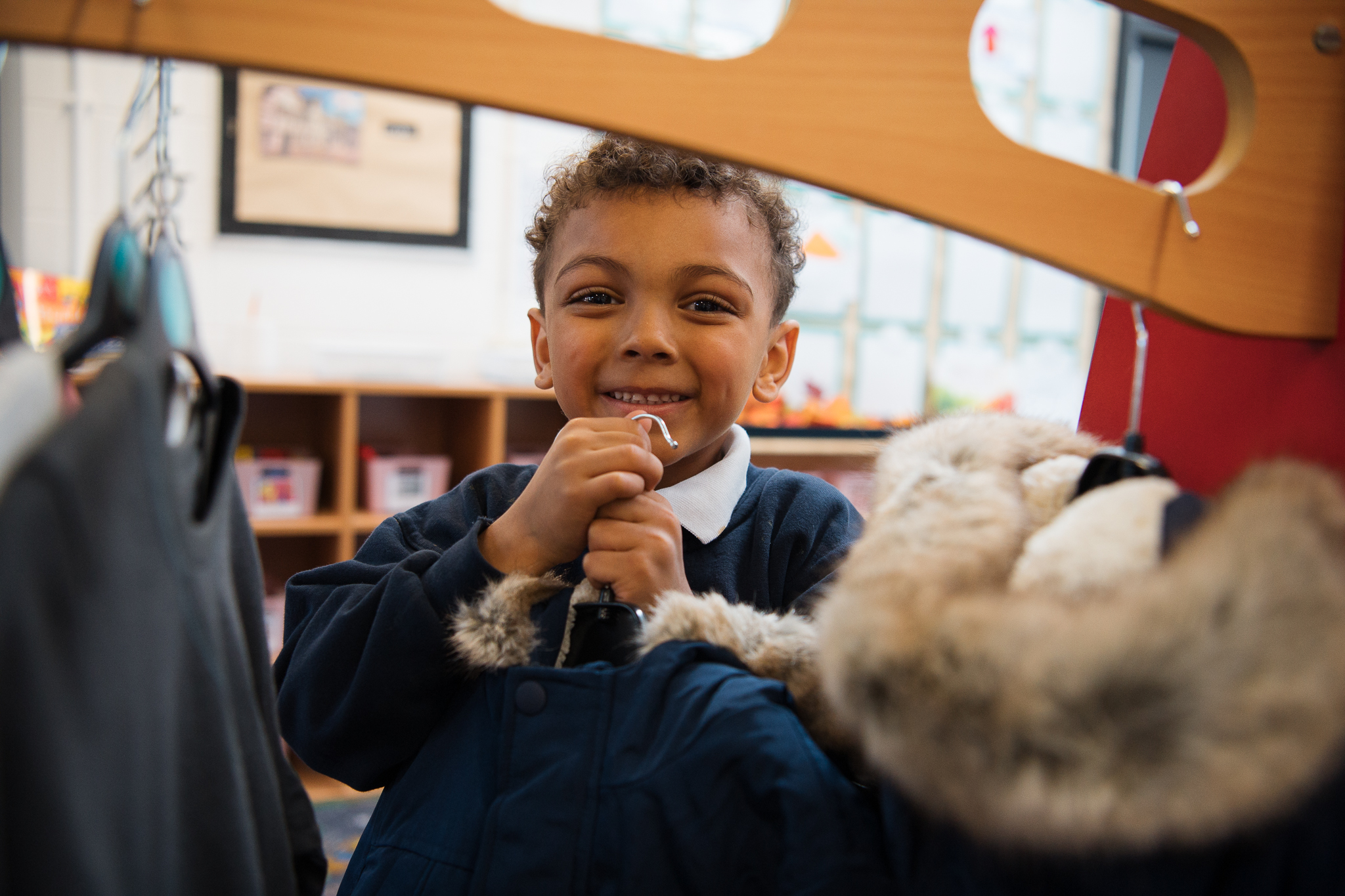Smiling child in school uniform holding a furry coat