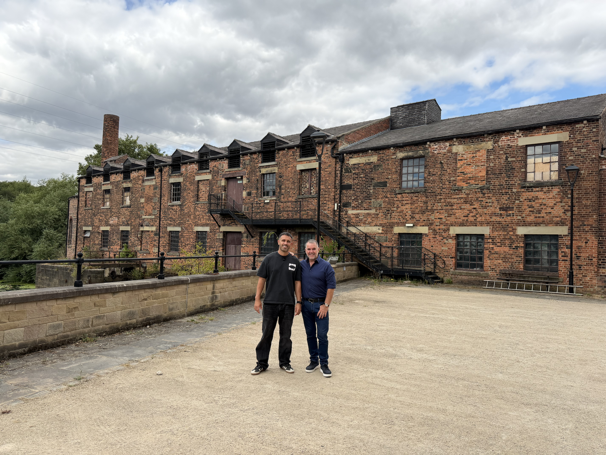 Historic red brick mill with metal staircases and two visitors