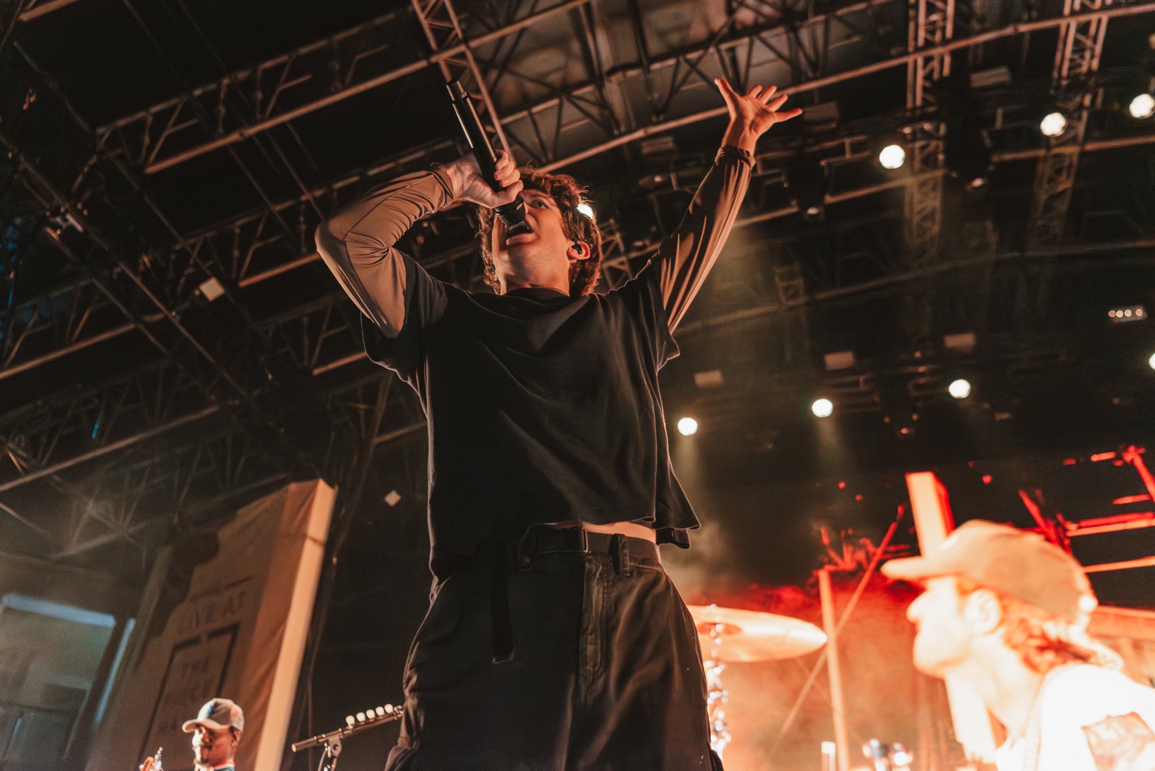 Energetic performer singing on stage with bright lights