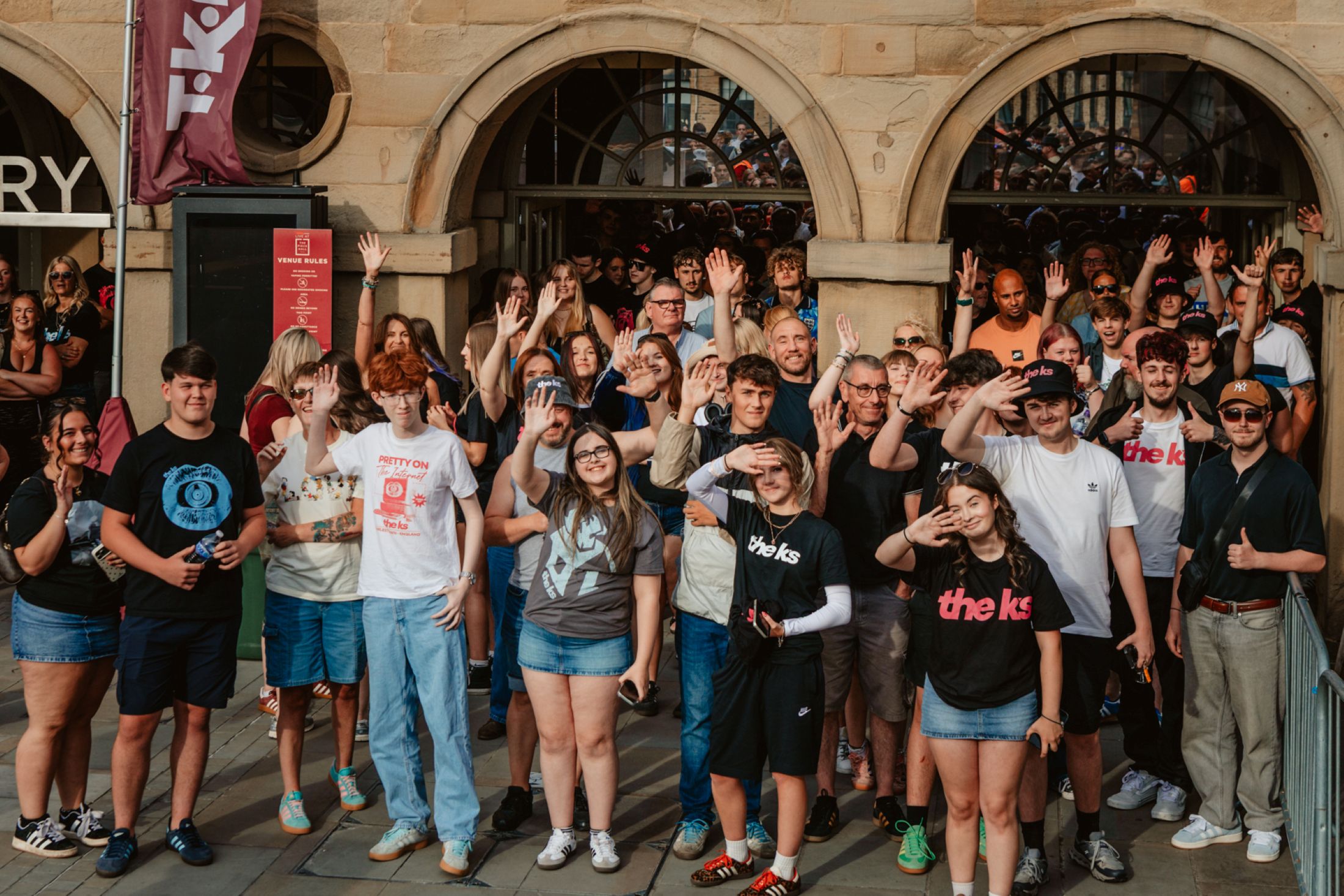 Group of cheerful people waving outside a historic building
