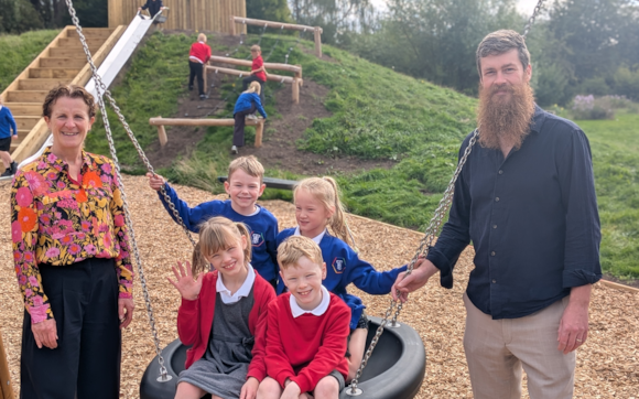 Children and adults at a playground with a slide and swings