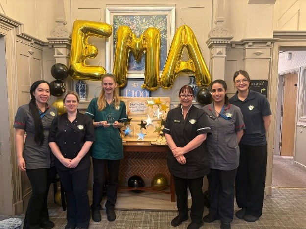 Group of six people in uniforms with EMA balloon decor