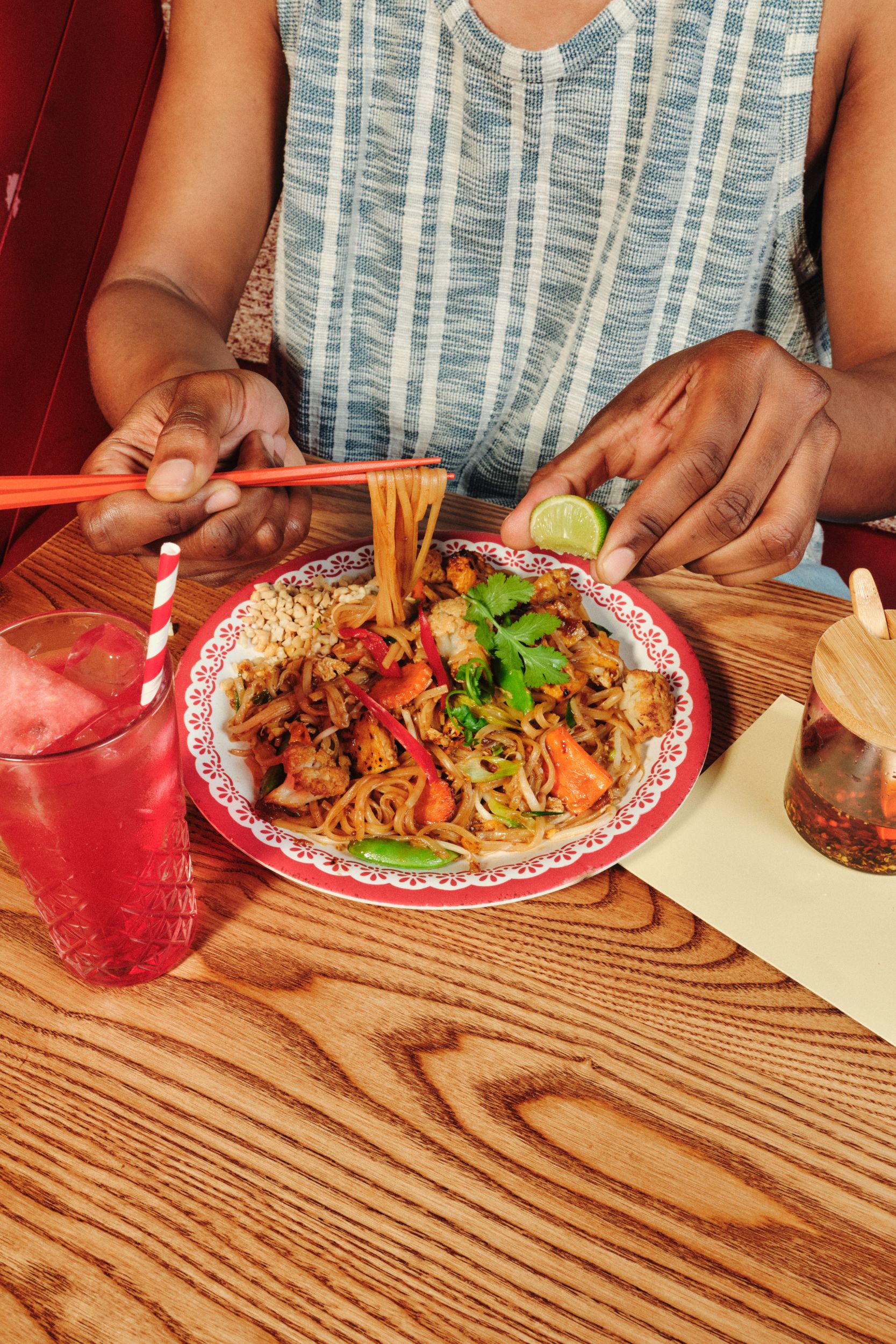 Person enjoying a colourful noodle dish with chopsticks at a cosy cafe