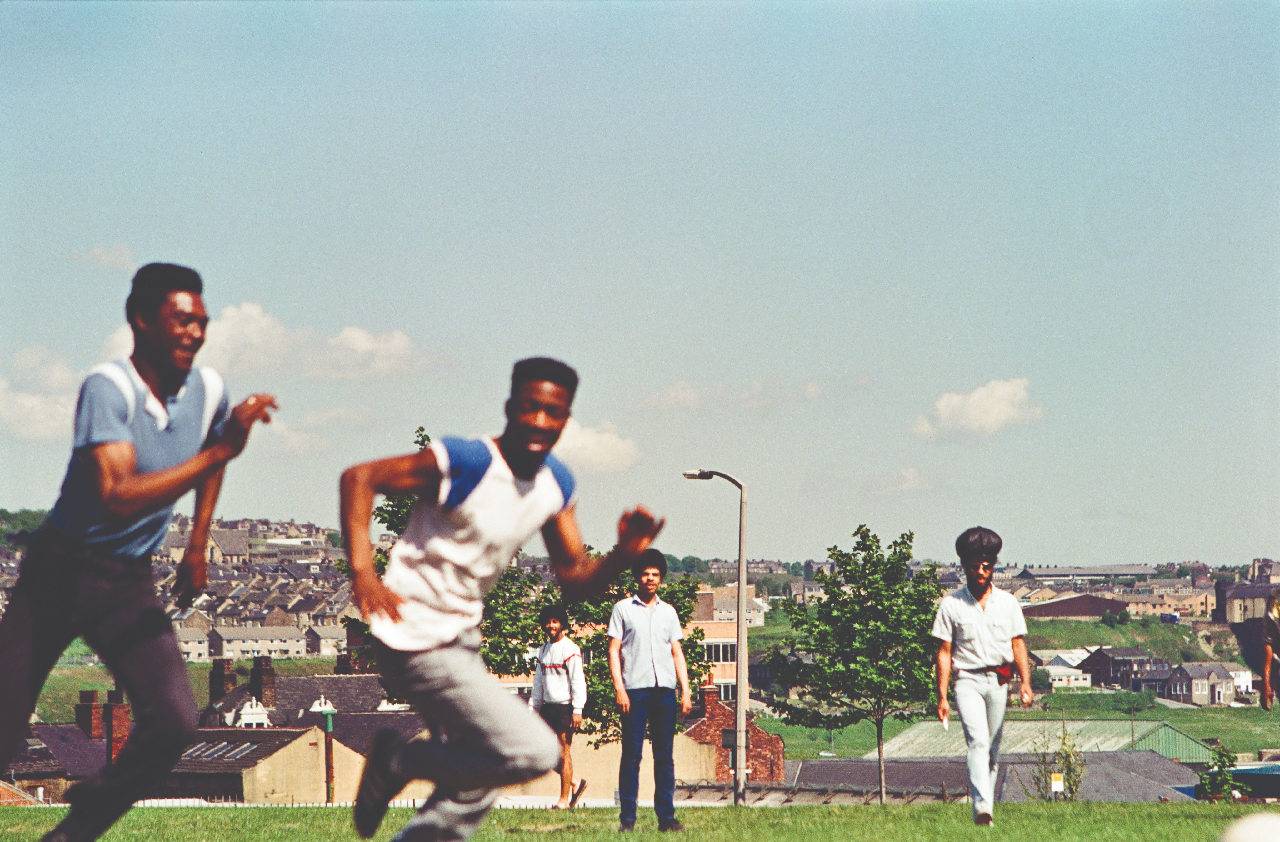Children playing on a sunny hillside with houses in the background