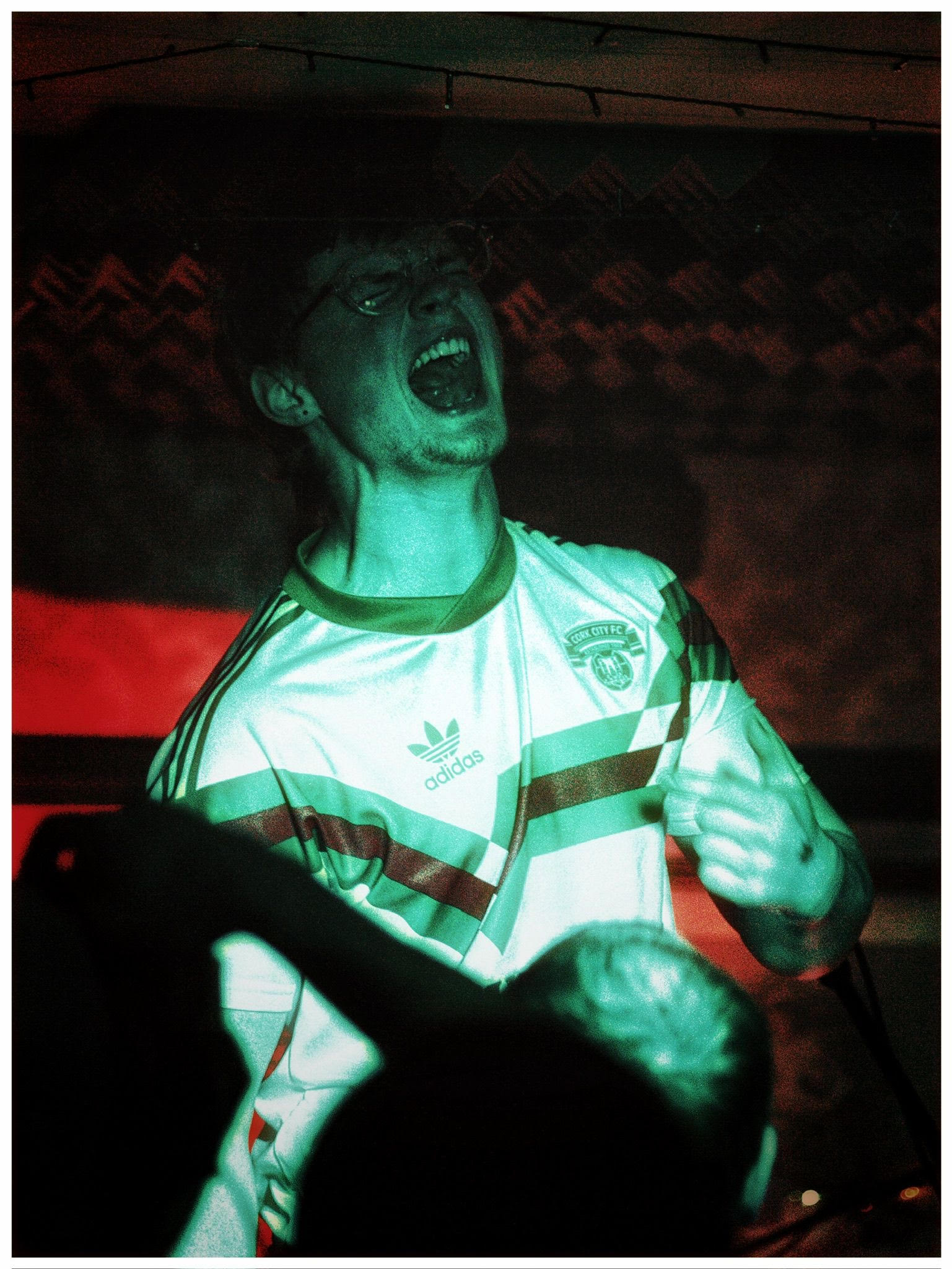 Man in a football shirt passionately cheering in a dimly lit room