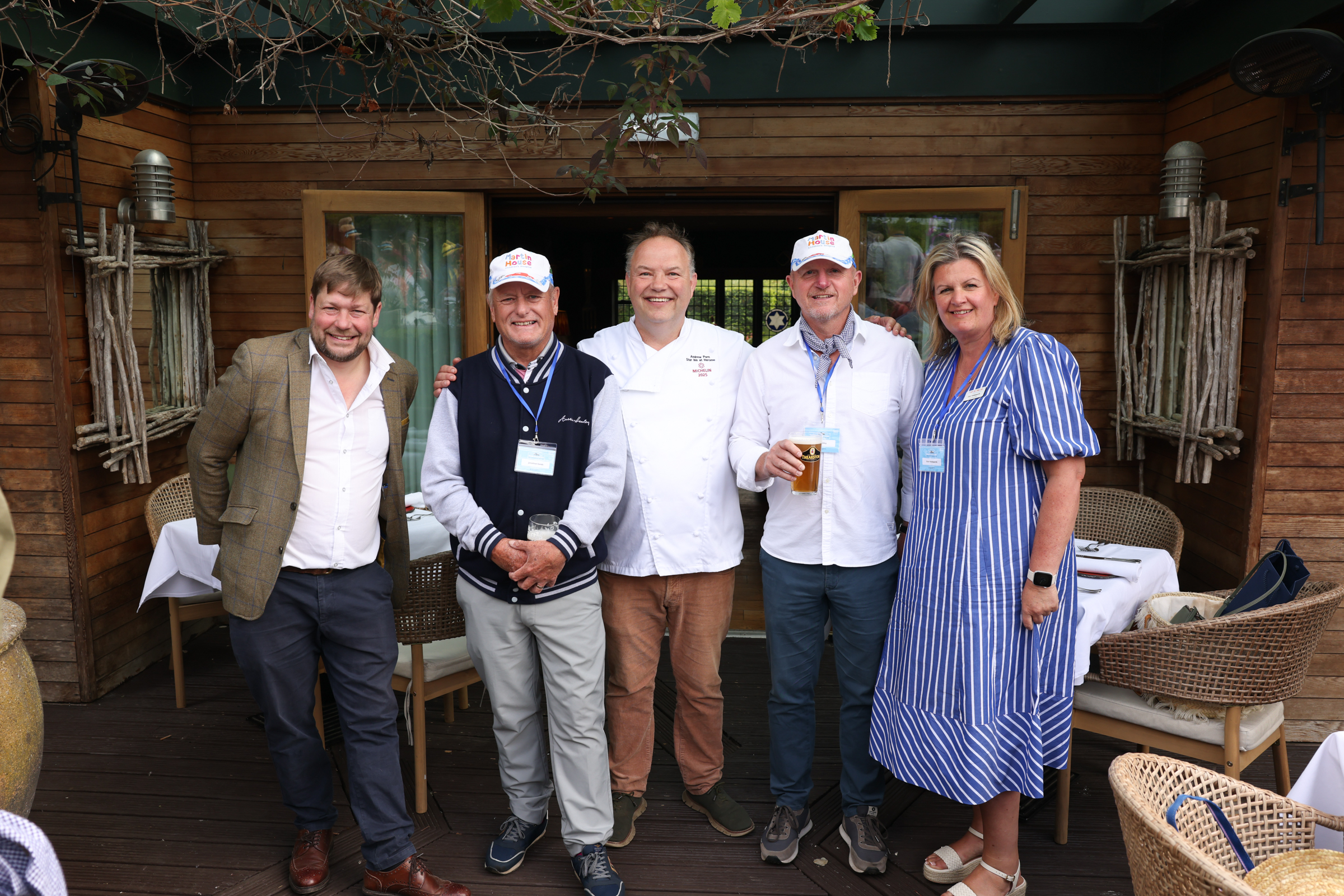 Smiling group of five people on a wooden patio with greenery