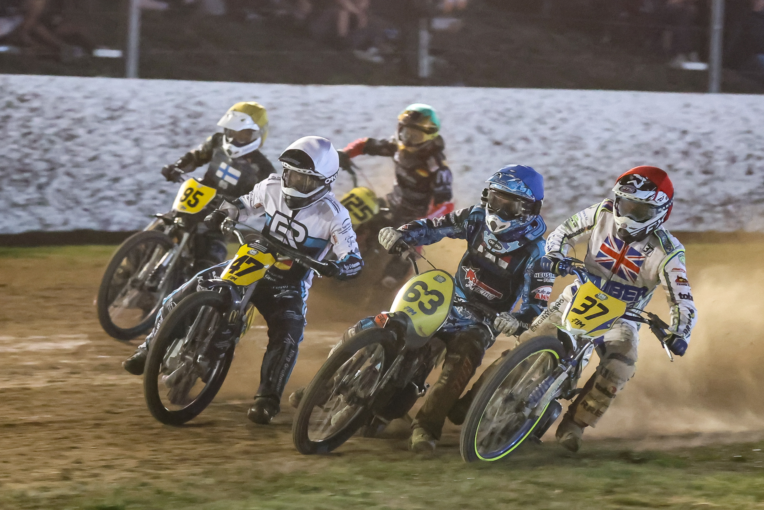 Motorcycle racers in action on dirt track at night