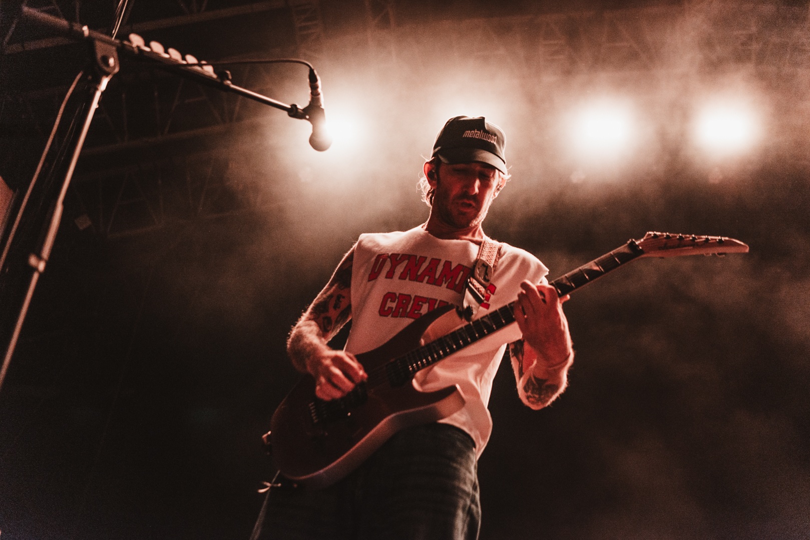 Musician playing electric guitar on stage with dramatic lighting