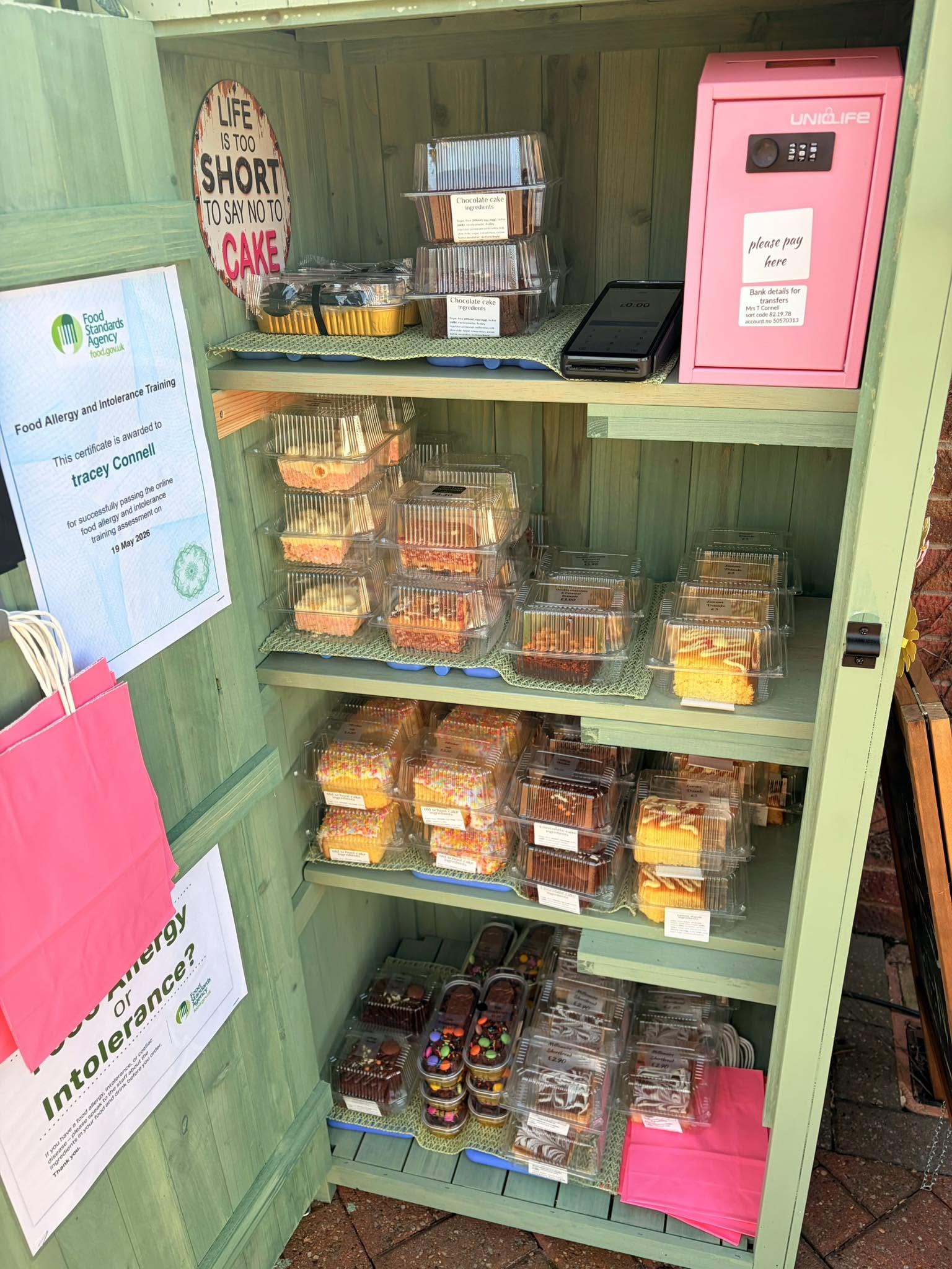 Wooden cabinet with shelves displaying assorted cakes