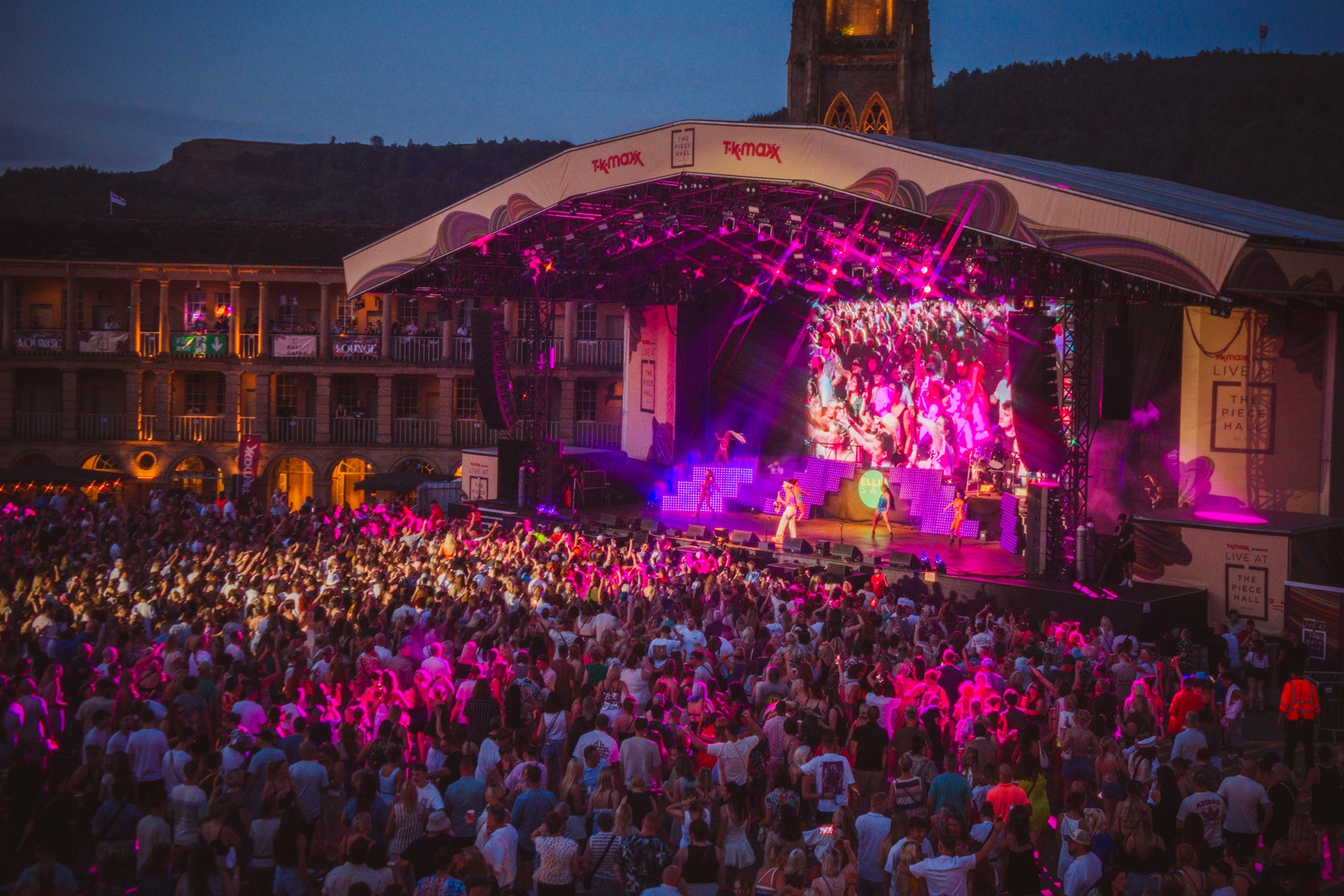 Crowd enjoying outdoor concert at dusk with illuminated stage - ELLIE SAXX AT THE PIECE HALL