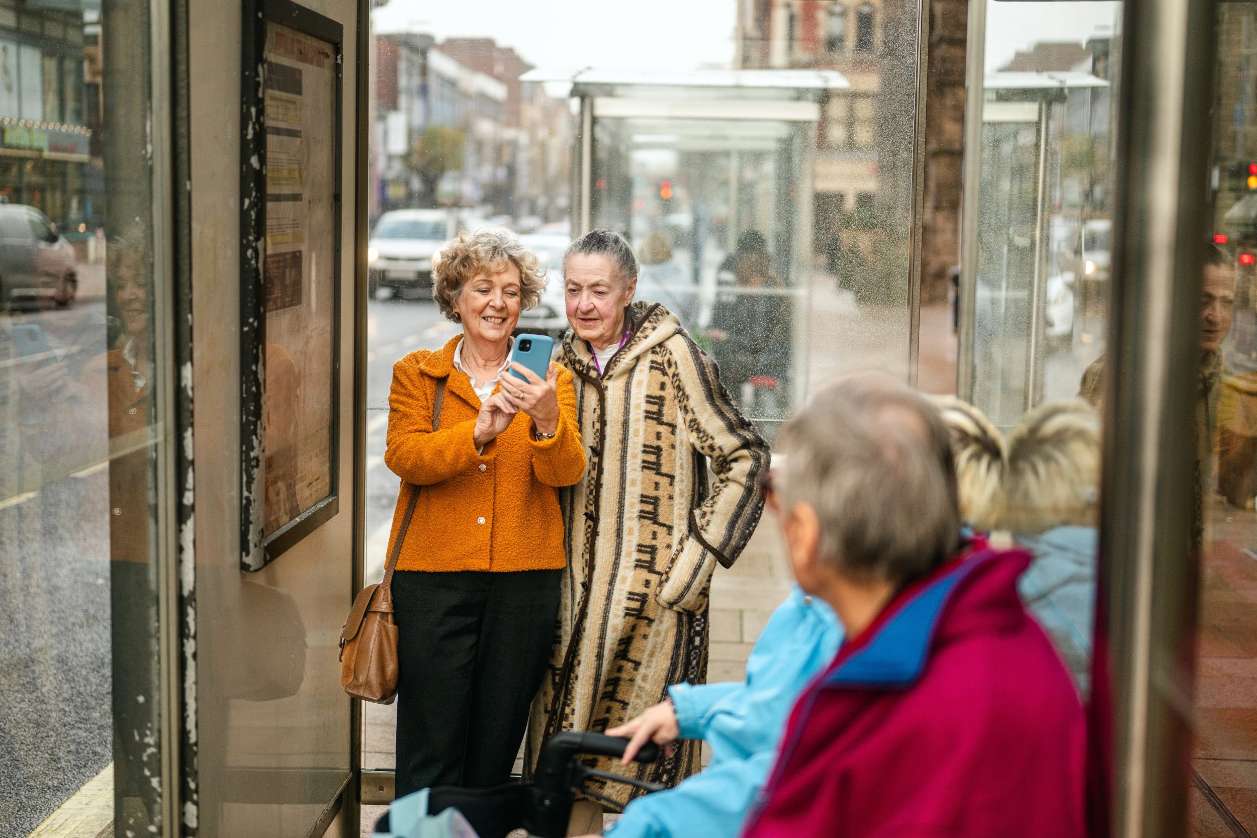 Elderly women smiling at phone in a modern bus shelter