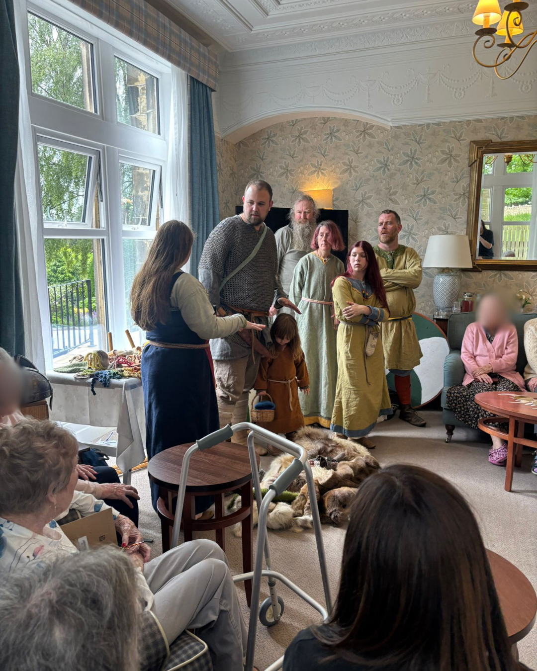 Group in medieval costumes presenting to seated audience indoors