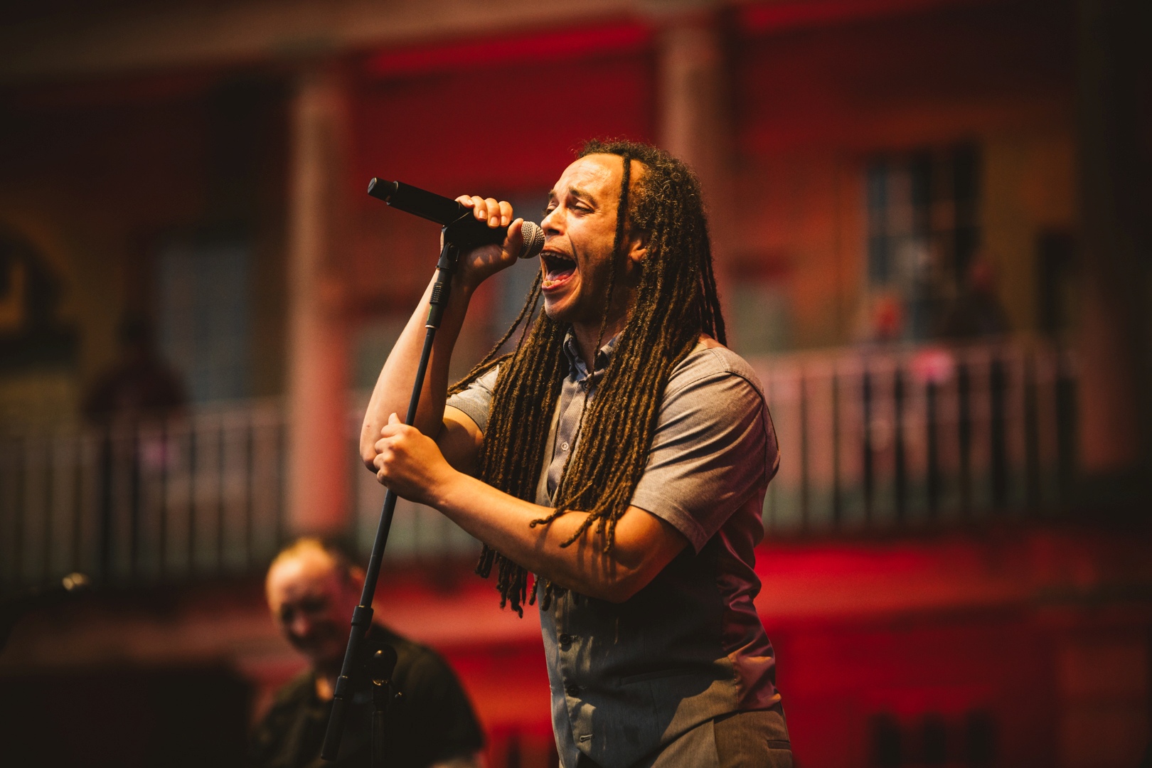 Musician with dreadlocks performing on outdoor stage