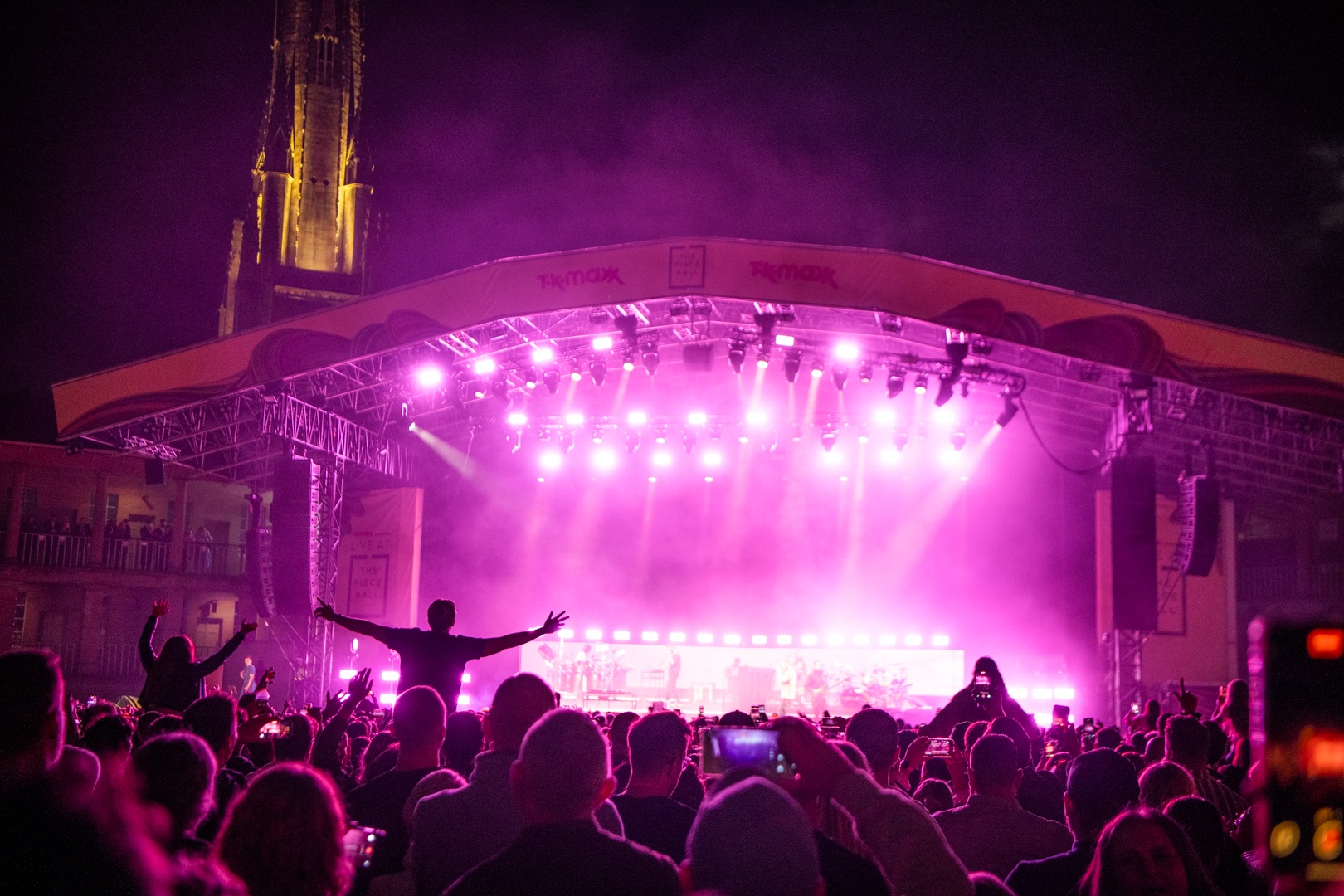 Crowd enjoying a night concert with pink stage lights