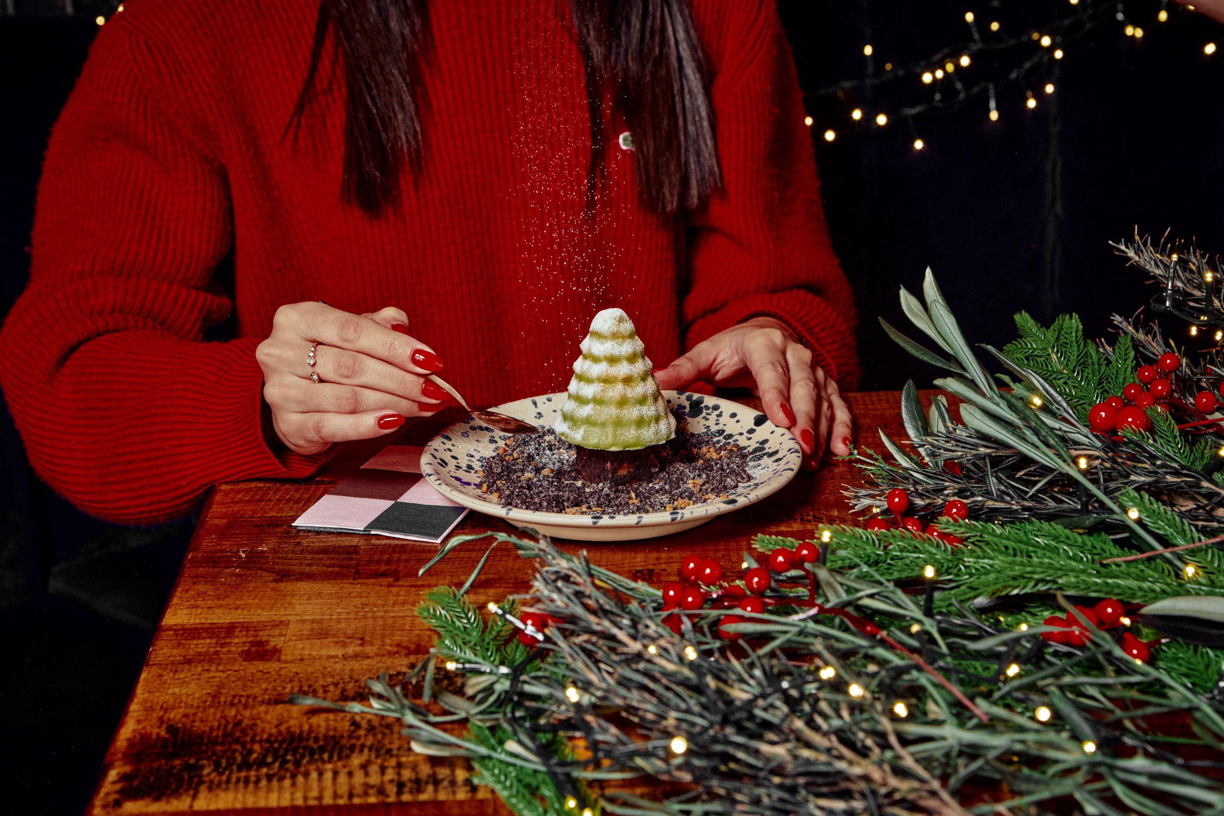 Festive dessert shaped like a tree on a wooden table with greenery