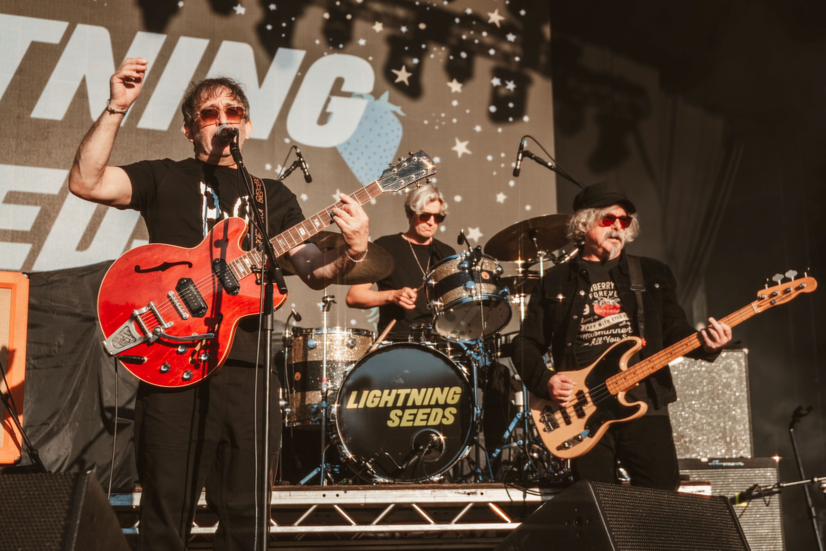 Band performing on stage with guitars and drums at festival