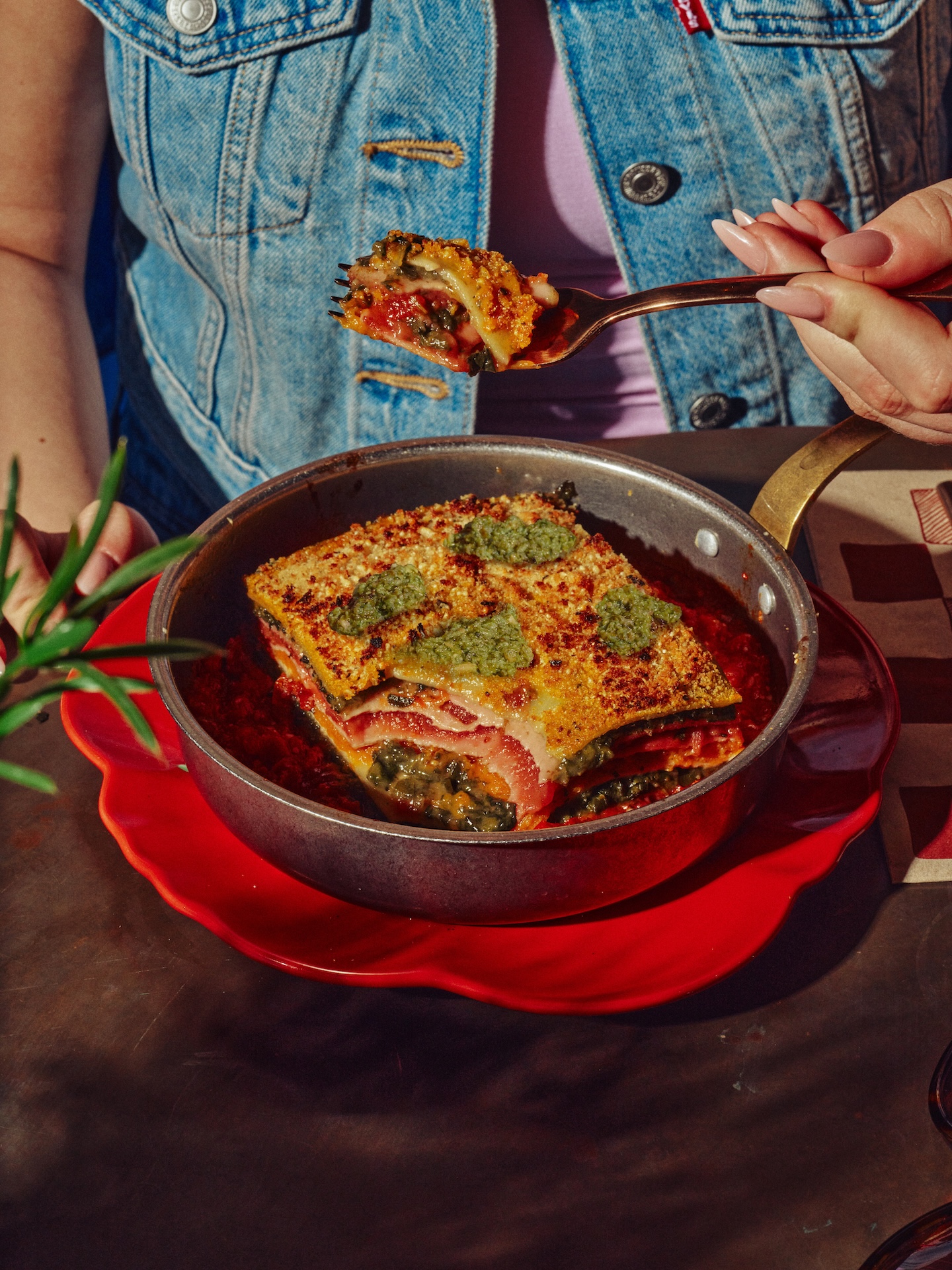 Close-up of layered lasagna in a pan with pesto topping