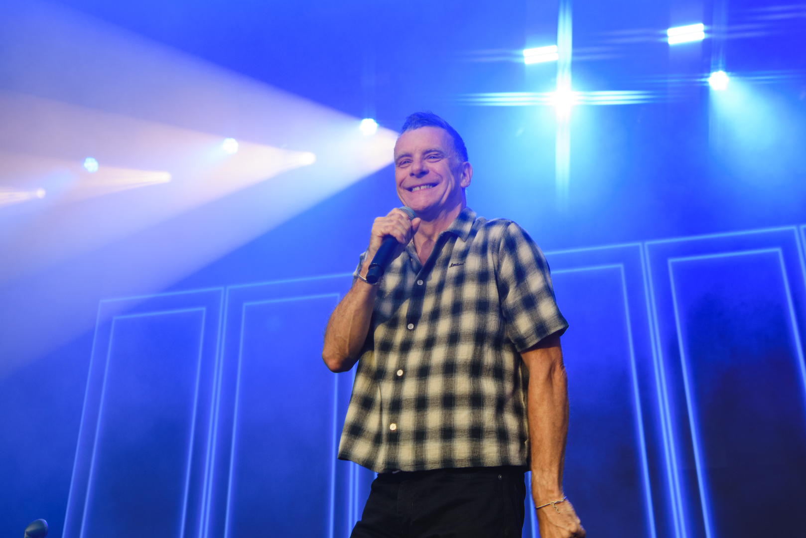 Smiling performer on stage with blue lights and microphone