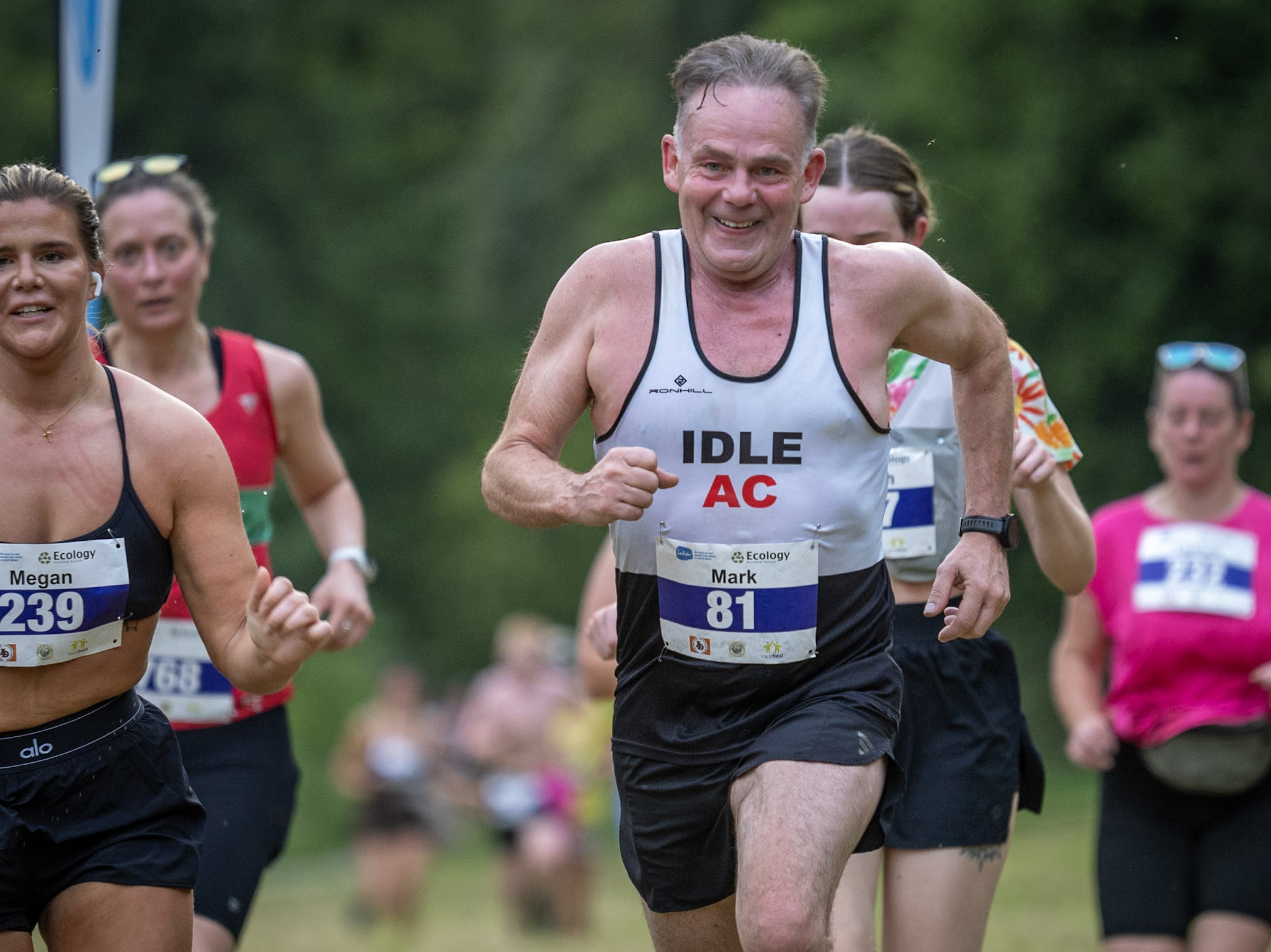 Group of runners in a forest race with smiling man in front