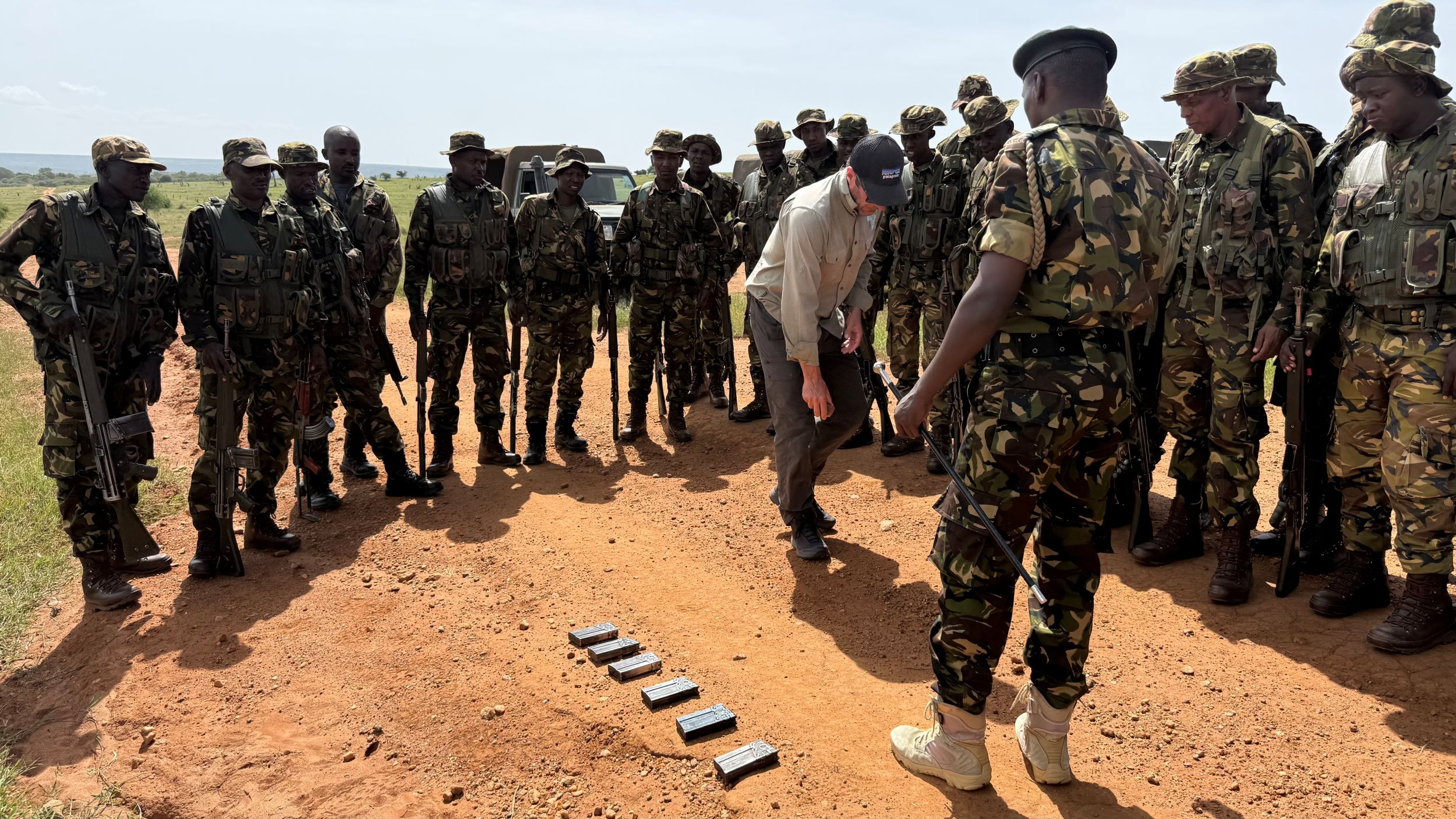 Group of soldiers in camouflage observing man on dirt path