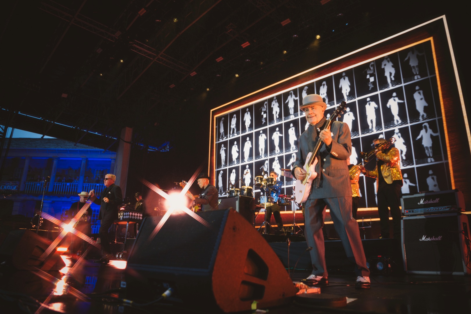 Band performing on stage with vibrant lighting and large screens