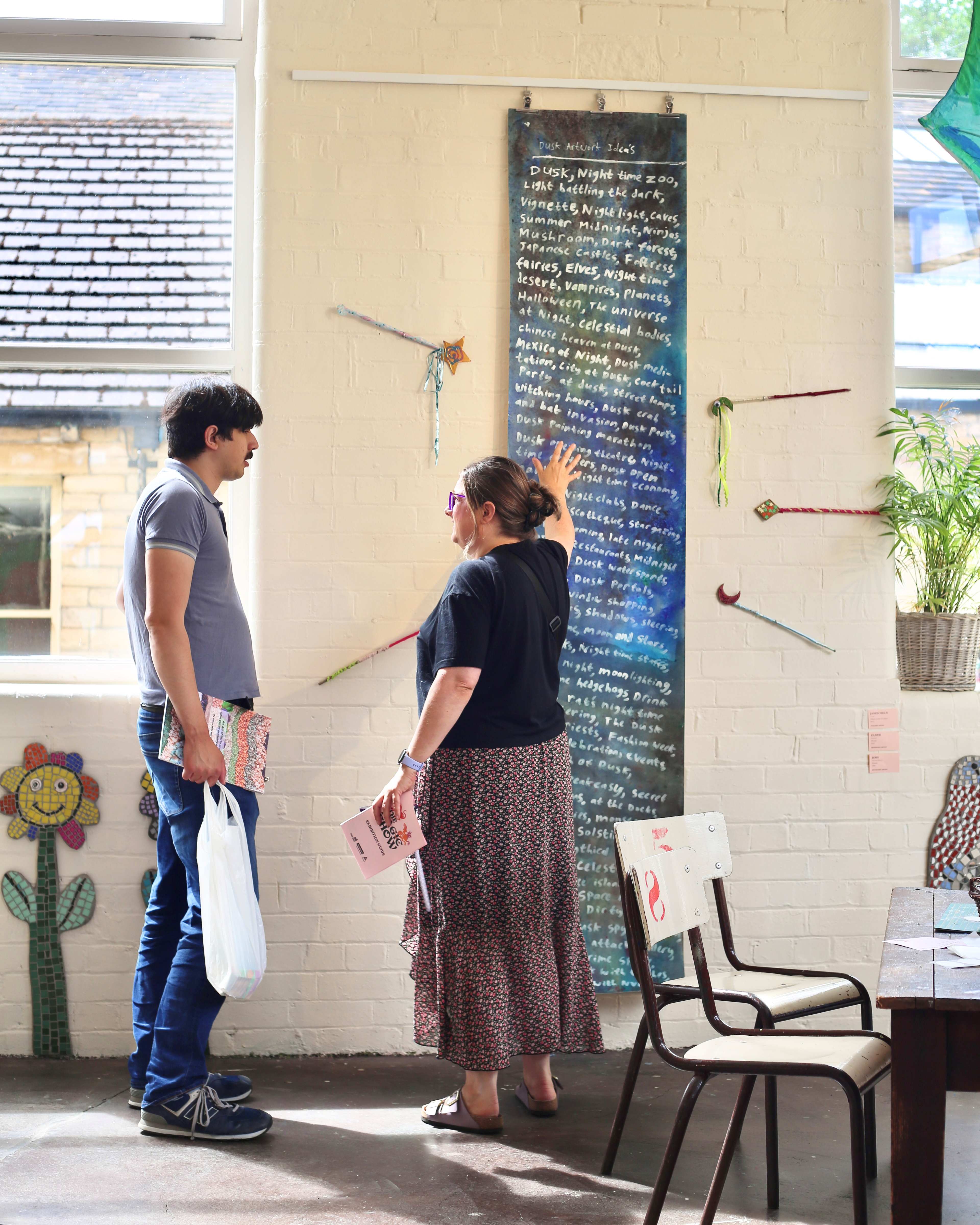 Two people reading colorful wall art in a bright gallery
