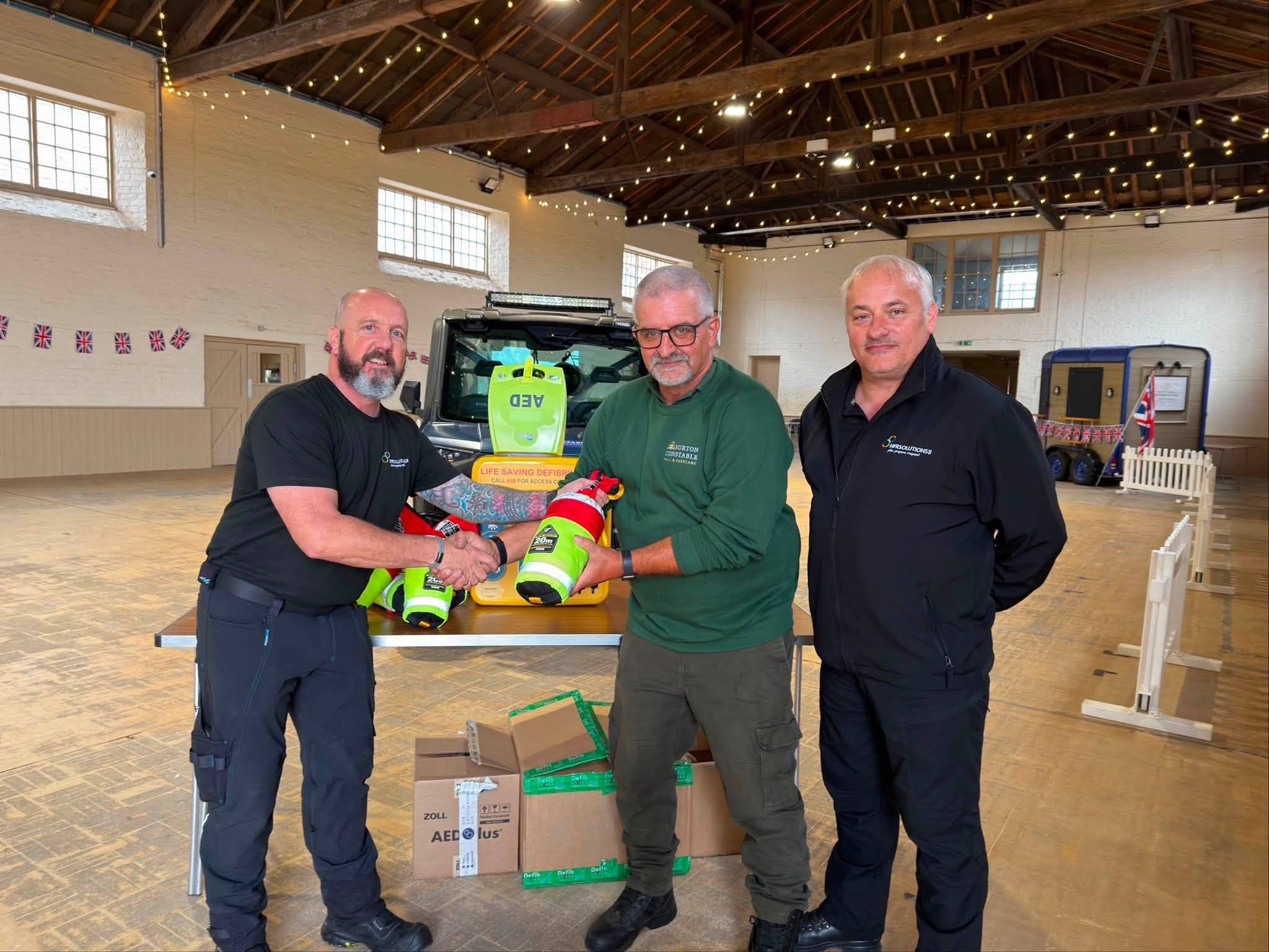 Three men in warehouse with defibrillator equipment