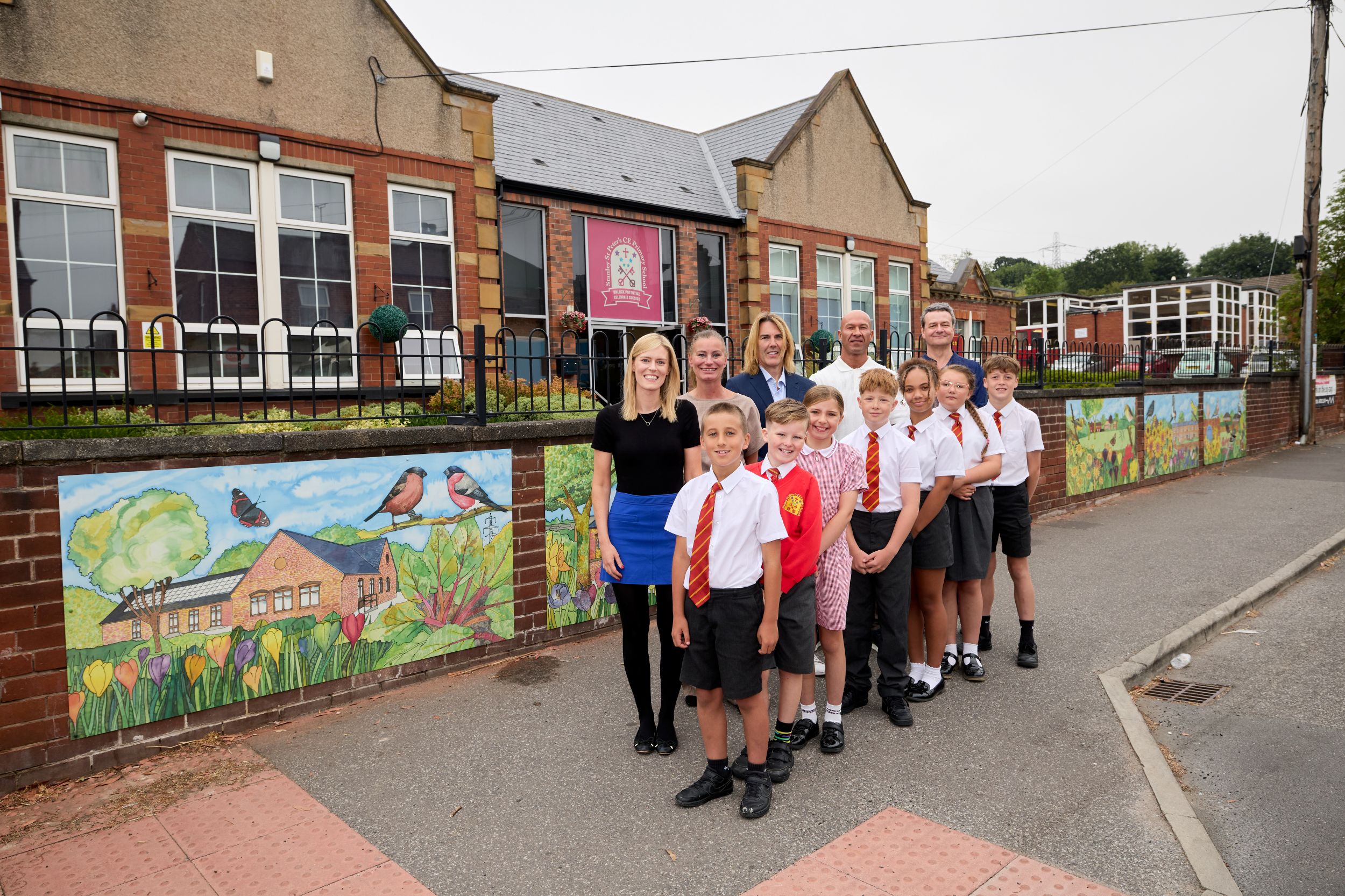 Primary school children and teachers outside a brick school building