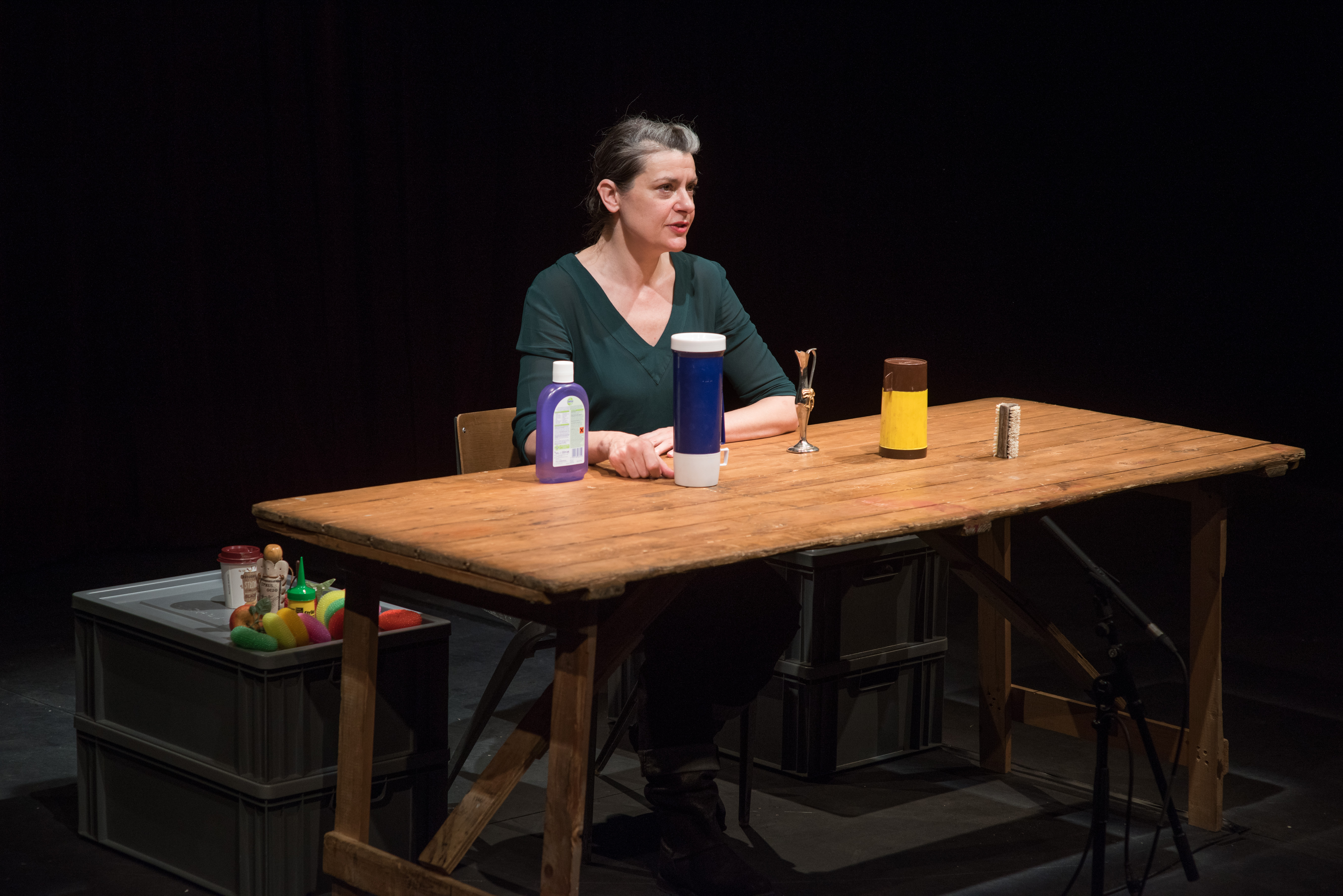 Woman seated at wooden table with cleaning products and trophy