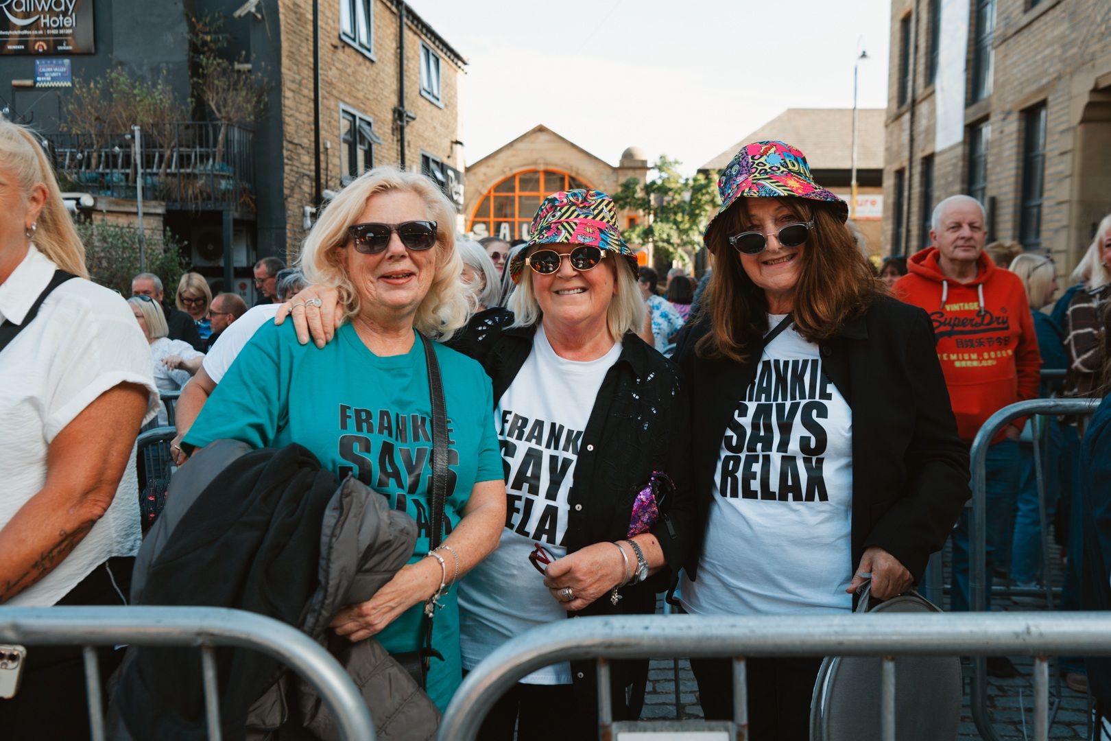 Three women in colourful hats and matching shirts at a street festival