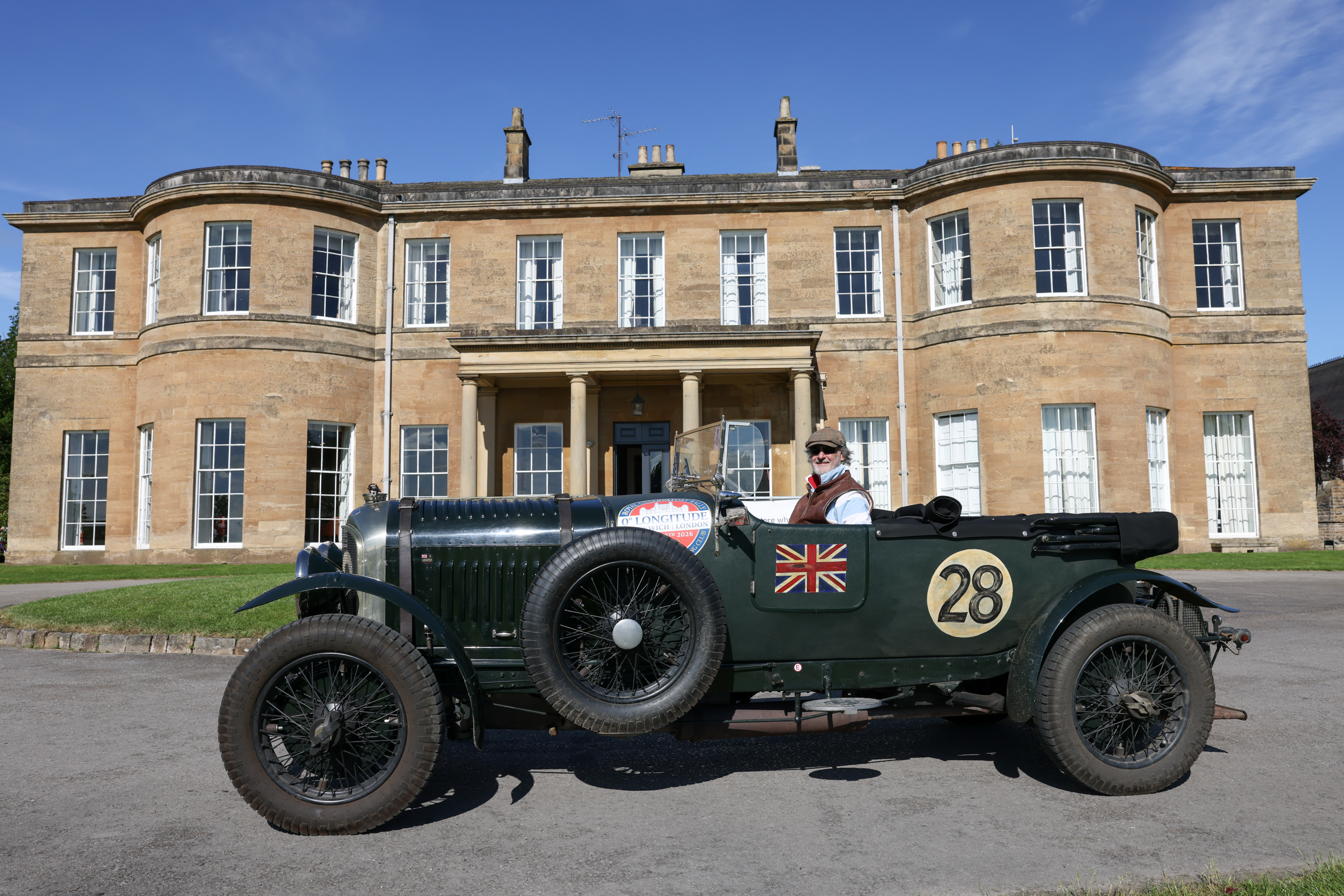 Vintage car parked in front of Georgian mansion with columns