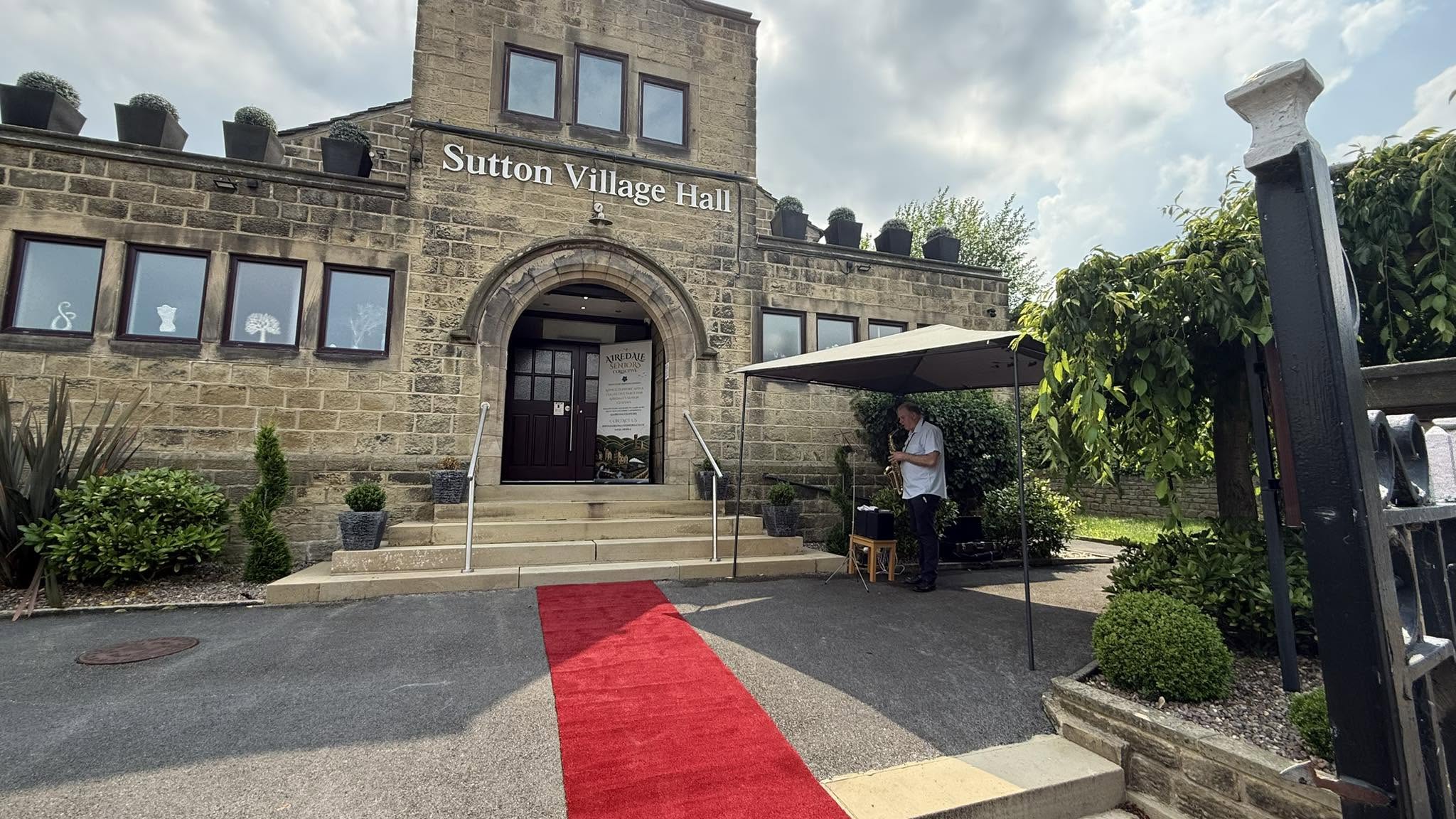 Stone village hall with red carpet and potted plants