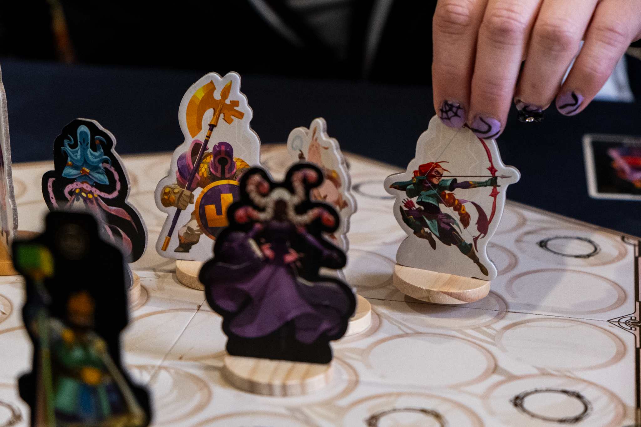 Hand arranging fantasy board game pieces on a game board