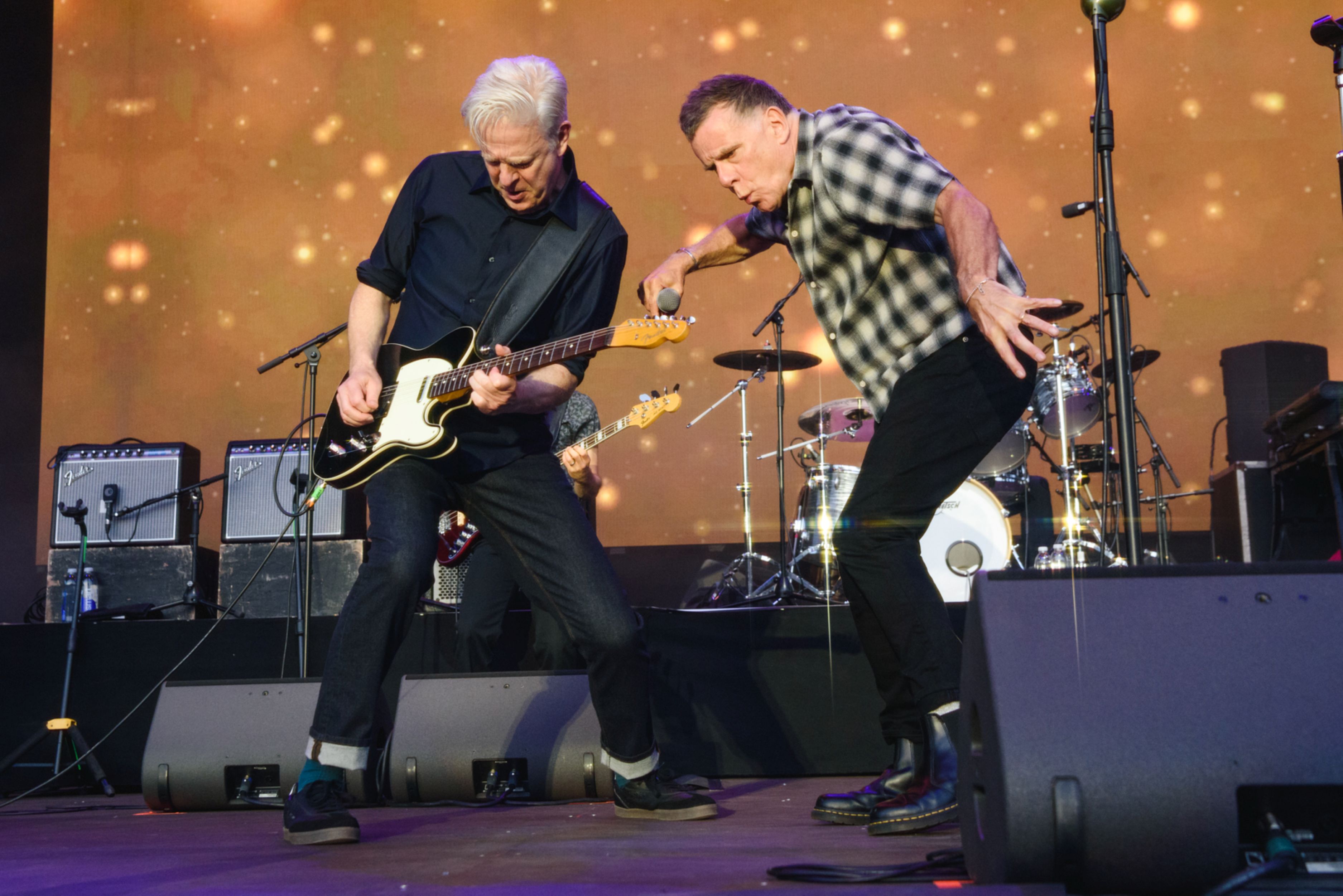 Two musicians performing energetically on stage with guitars