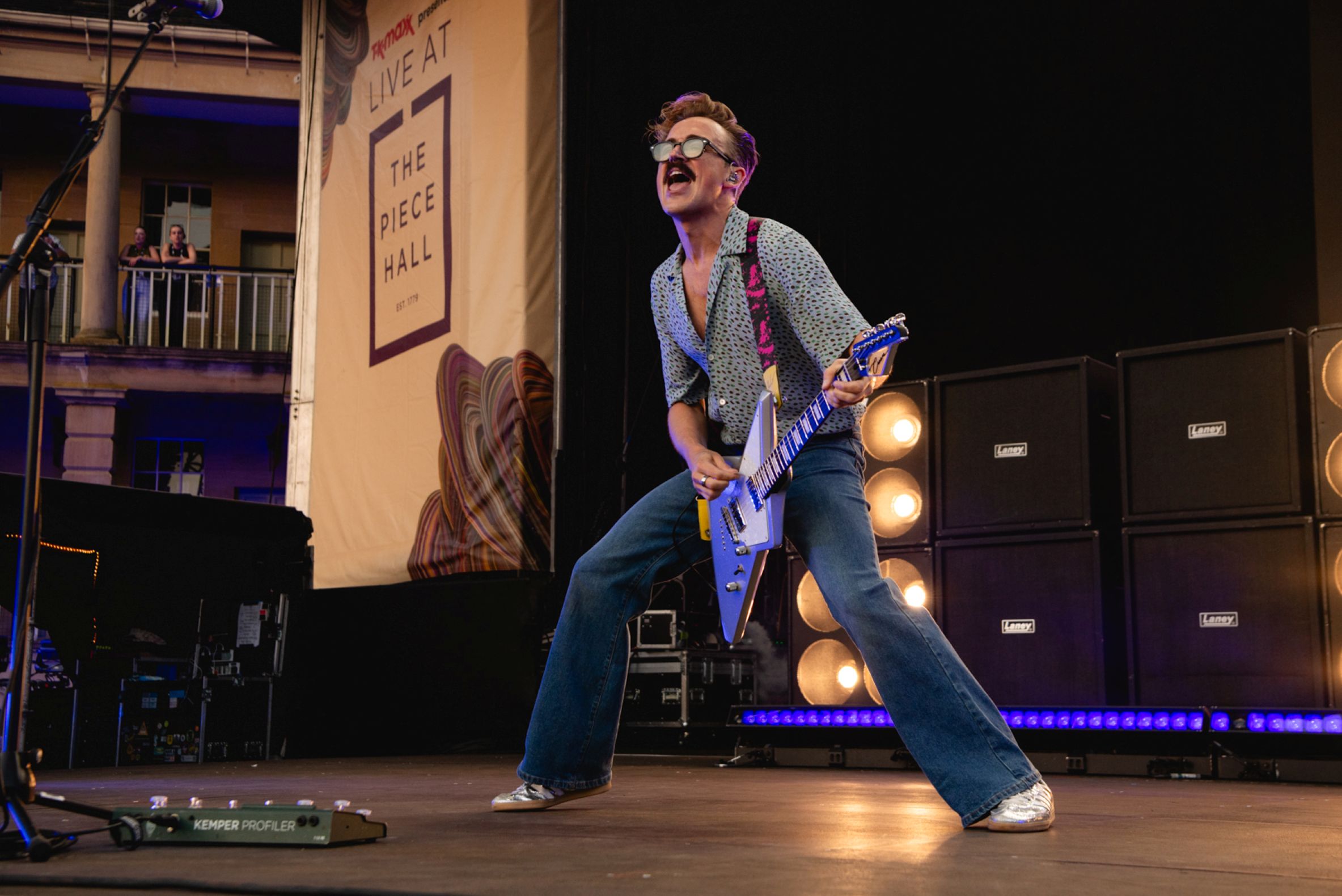 Guitarist performing energetically on stage at The Piece Hall