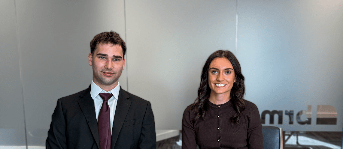 Smiling man and woman in formal attire in modern office