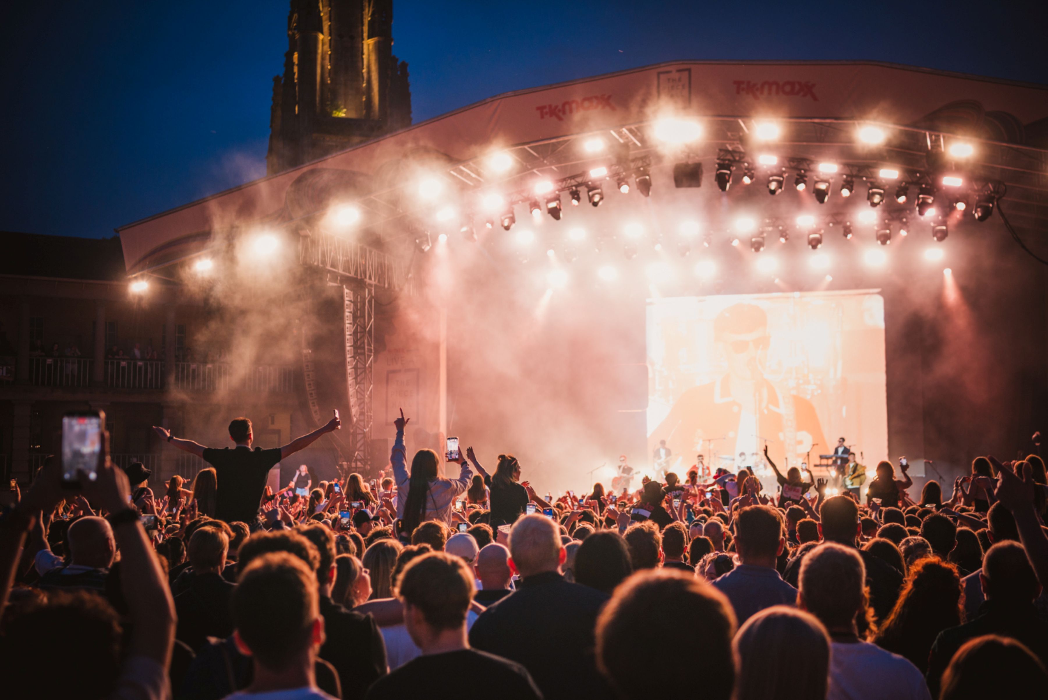 Crowd enjoying an outdoor concert with illuminated stage at night