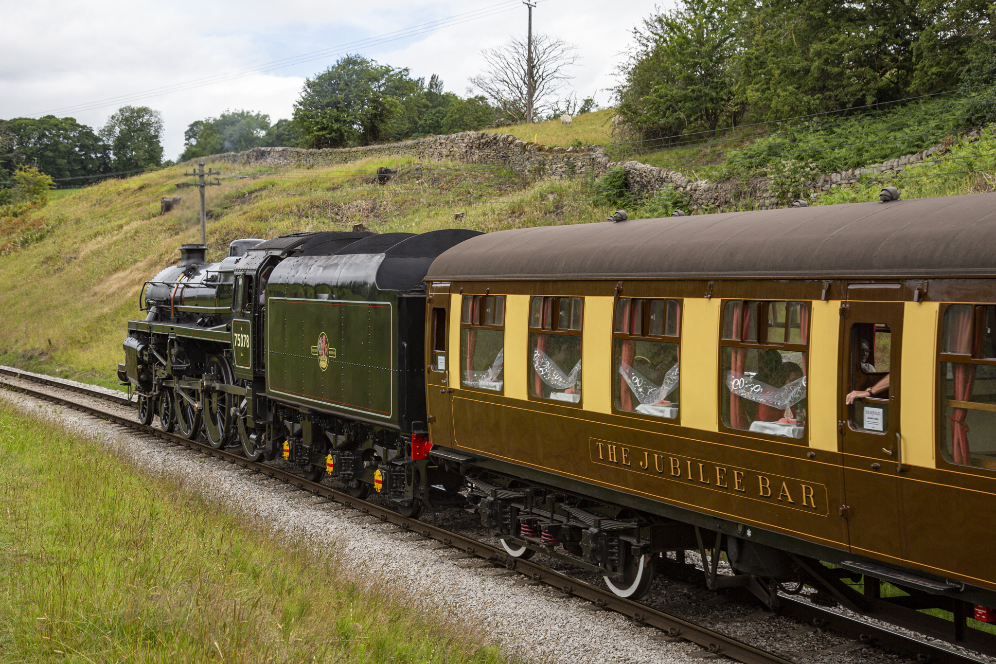 Historic steam train with brown and cream carriages on Yorkshire Dales railway