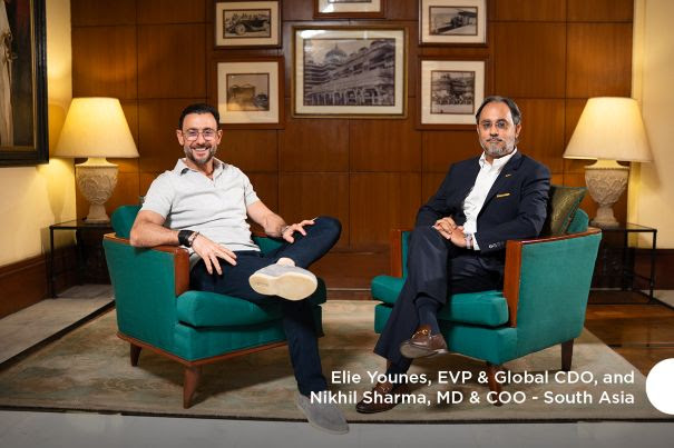 Two men seated on green armchairs in a formal office setting