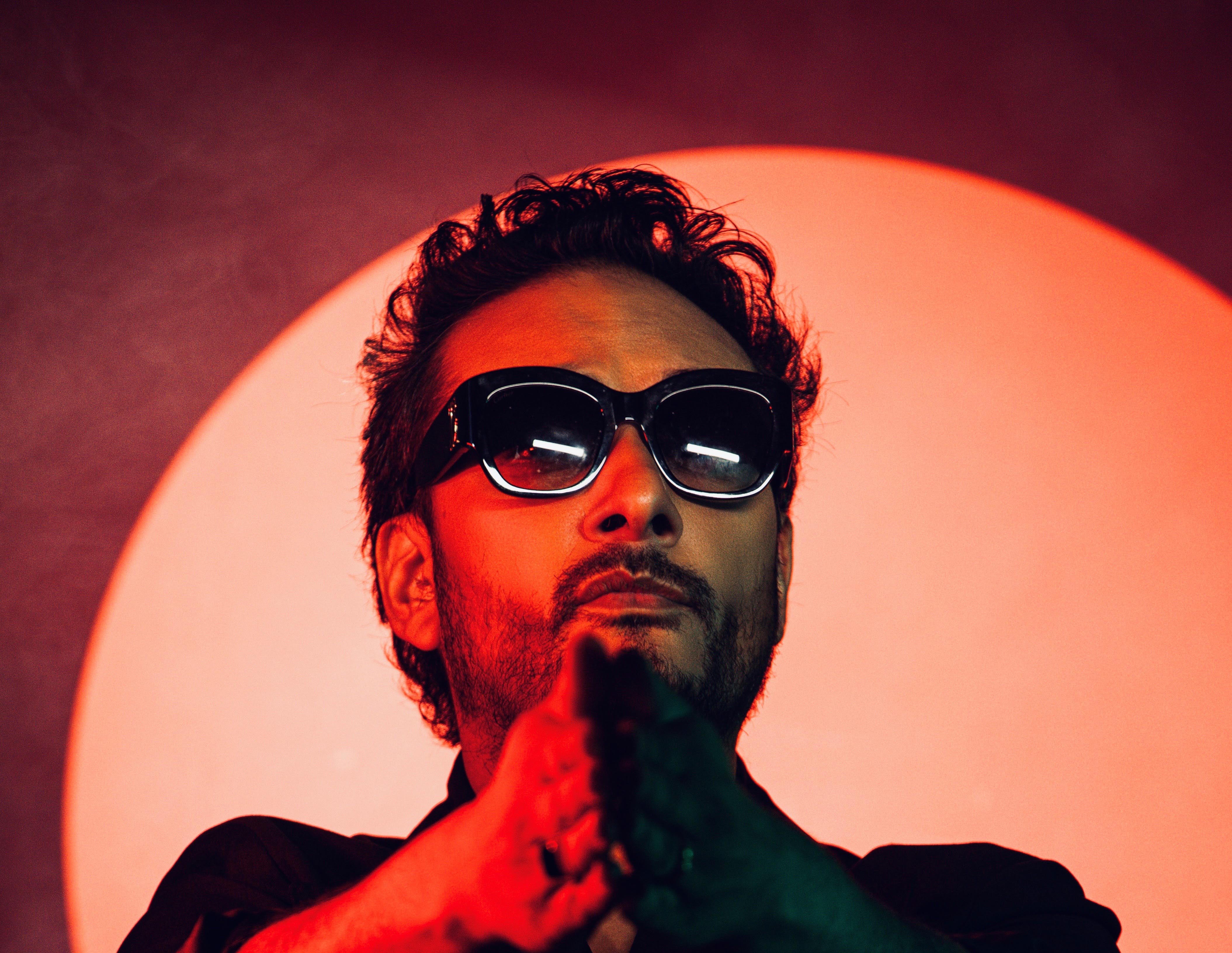 Man in sunglasses with clasped hands, red circular background
