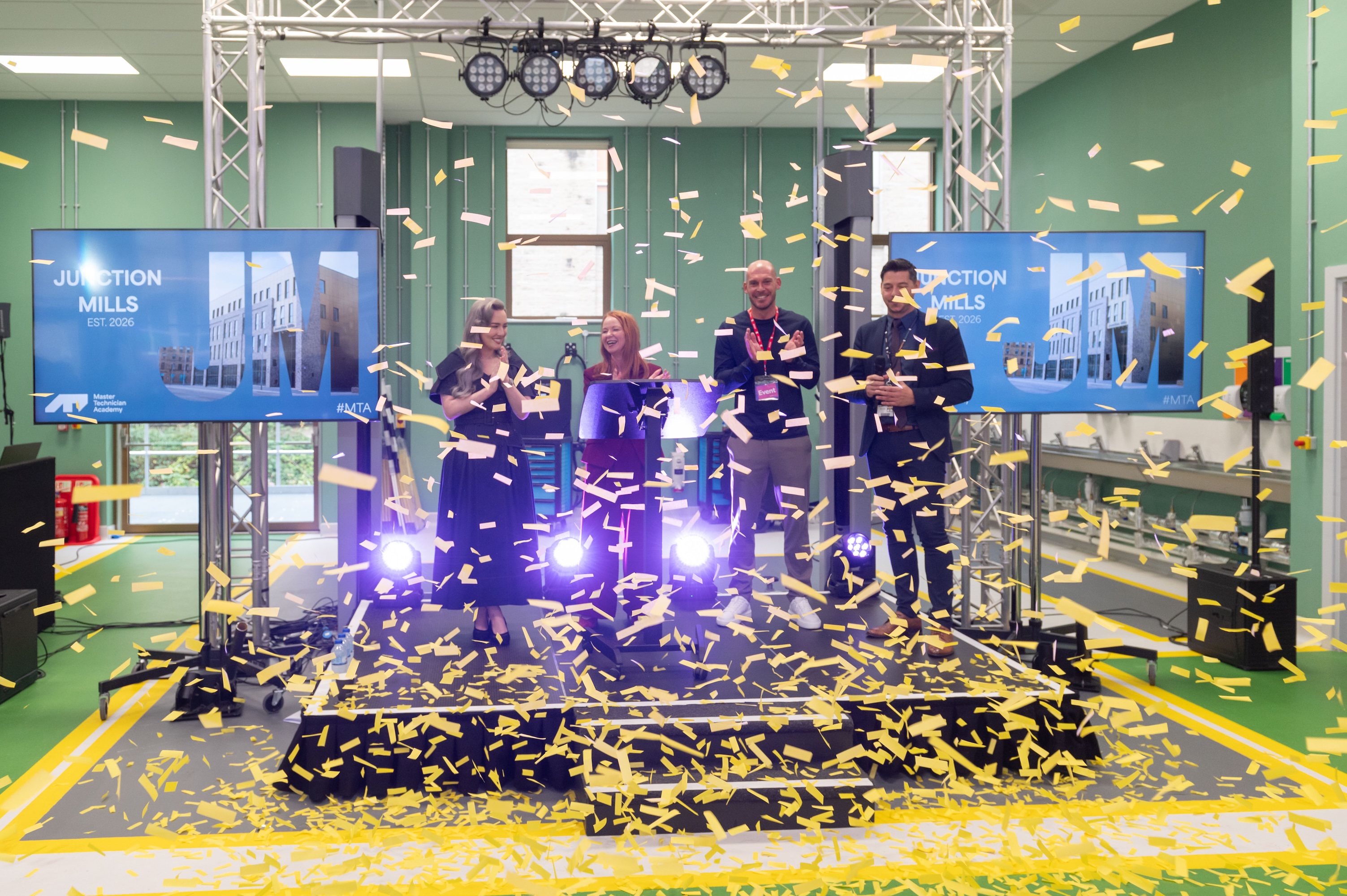 People celebrating in a modern room with yellow confetti and screens