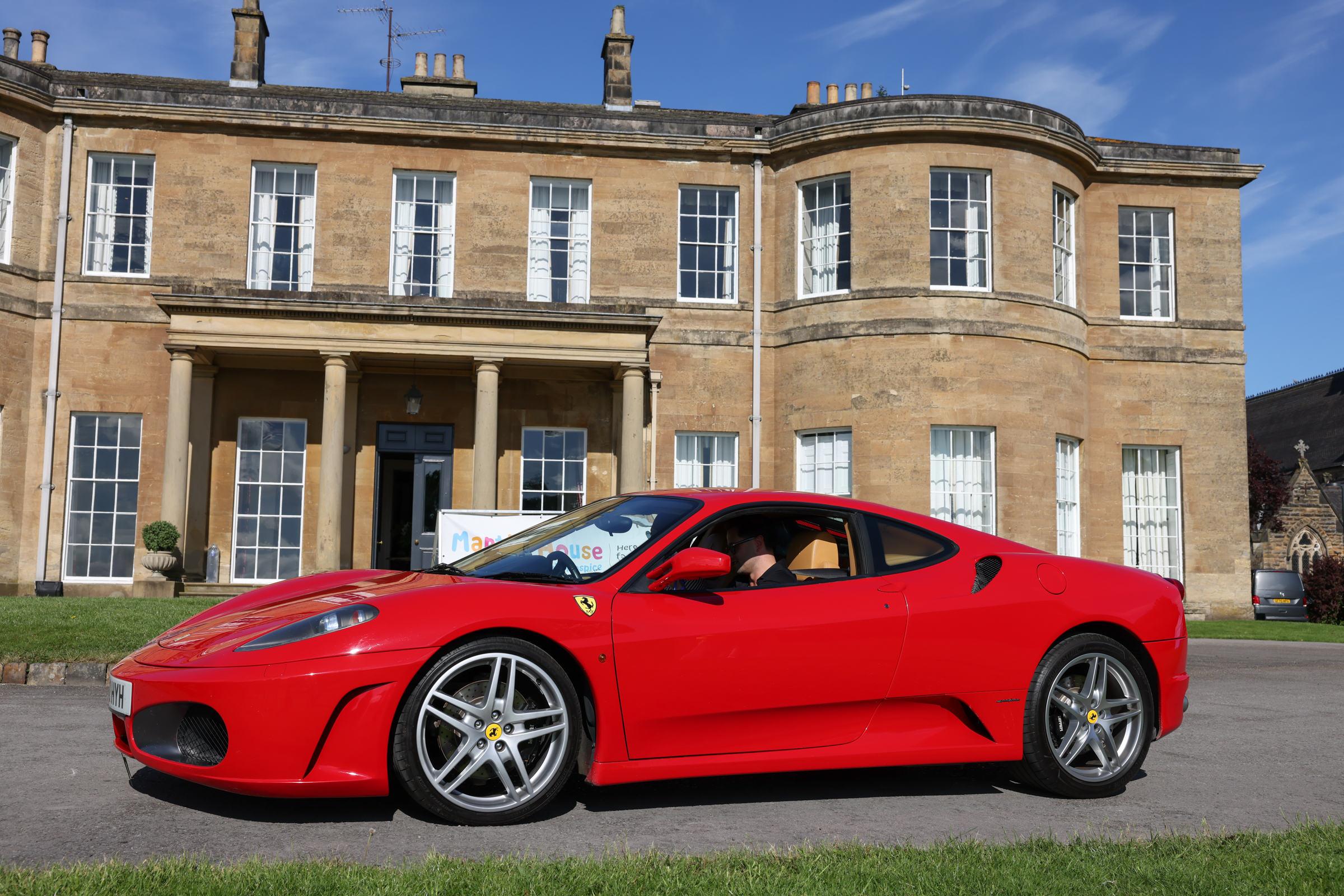 Red sports car parked in front of Georgian mansion