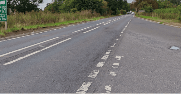 Quiet country road lined with green hedges and trees in Yorkshire